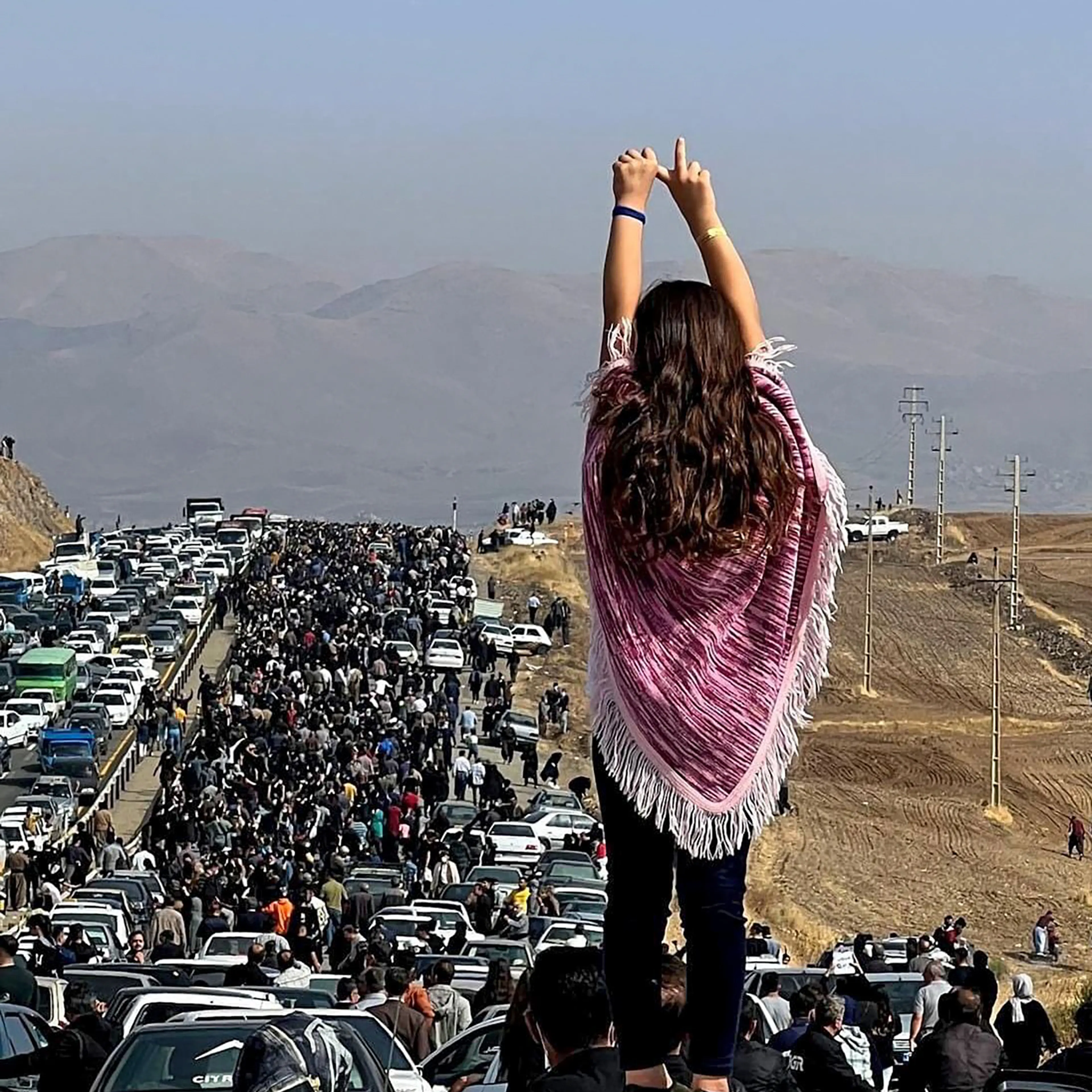 An unveiled woman standing on top of a vehicle as thousands make their way towards Aichi cemetery in Saqez, Mahsa Amini's home town in the western Iranian province of Kurdistan, to mark 40 days since her death, defying heightened security measures as part of a bloody crackdown on women-led protests.