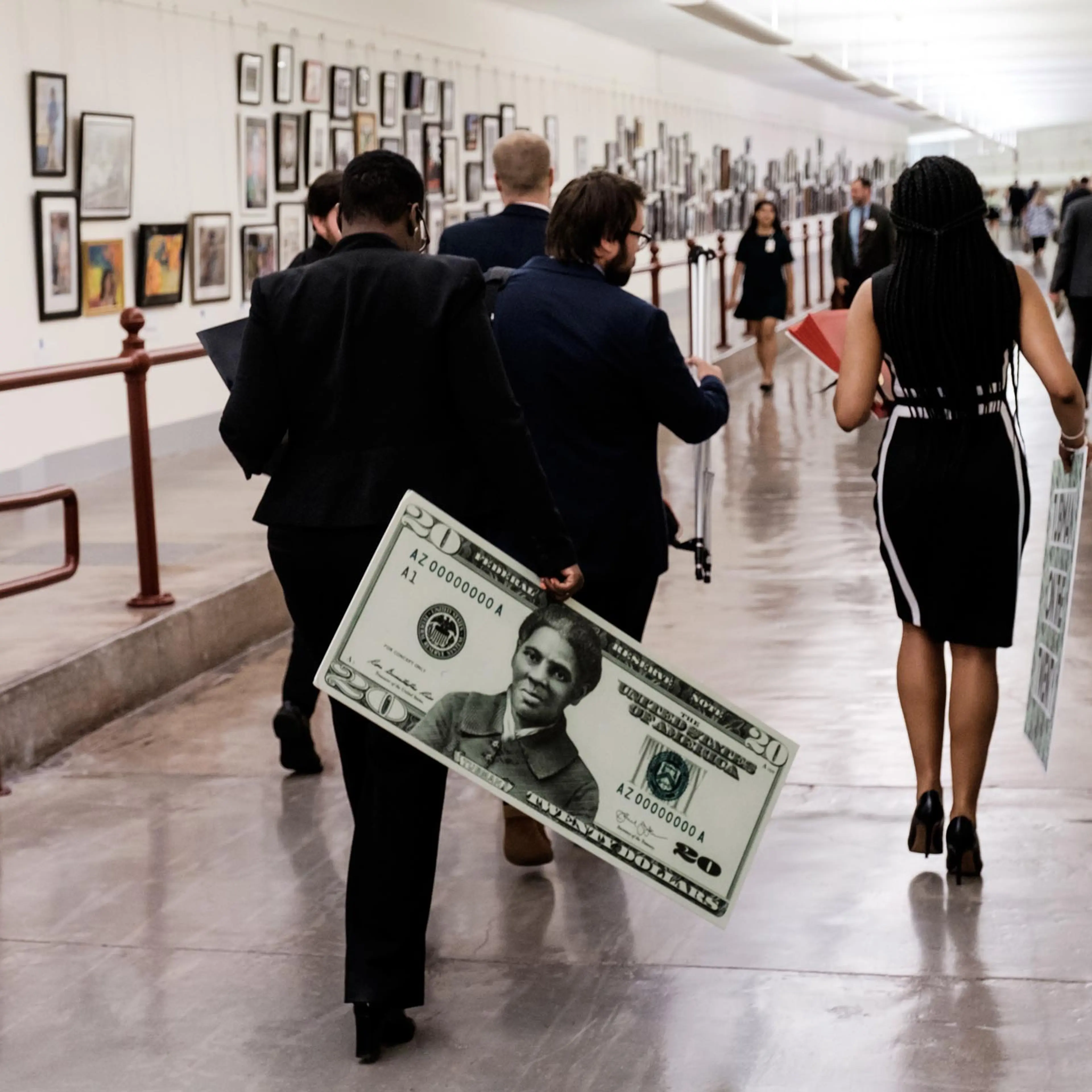 A congressional staffer departs holding a visual aide following a news conference regarding the redesigned $20 bill meant to honor Harriet Tubman.