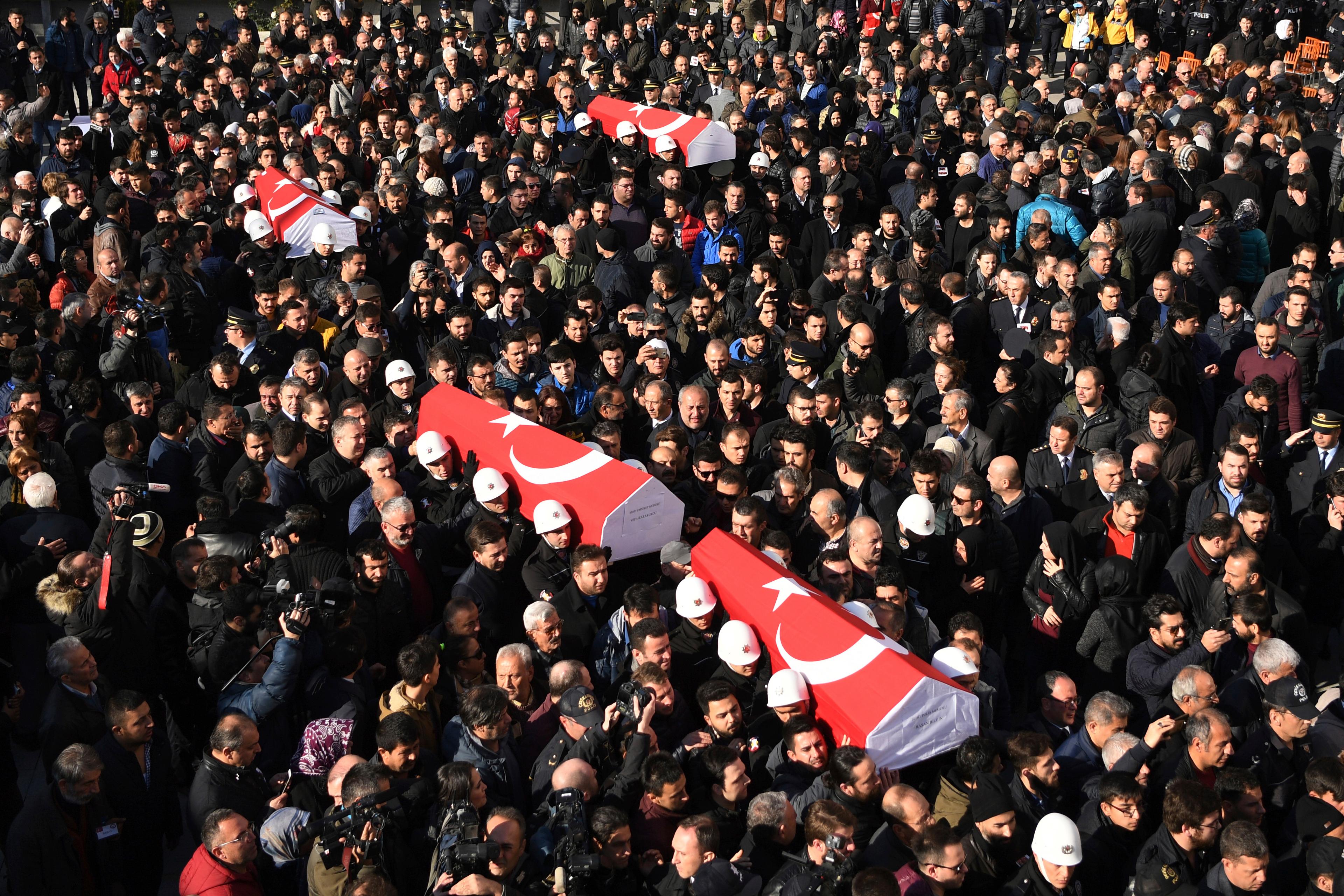People carry the coffins of bomb victims during a memorial in Istanbul, Dec. 11, 2016, for police officers killed outside the Besiktas football club stadium Vodafone Arena late Saturday.