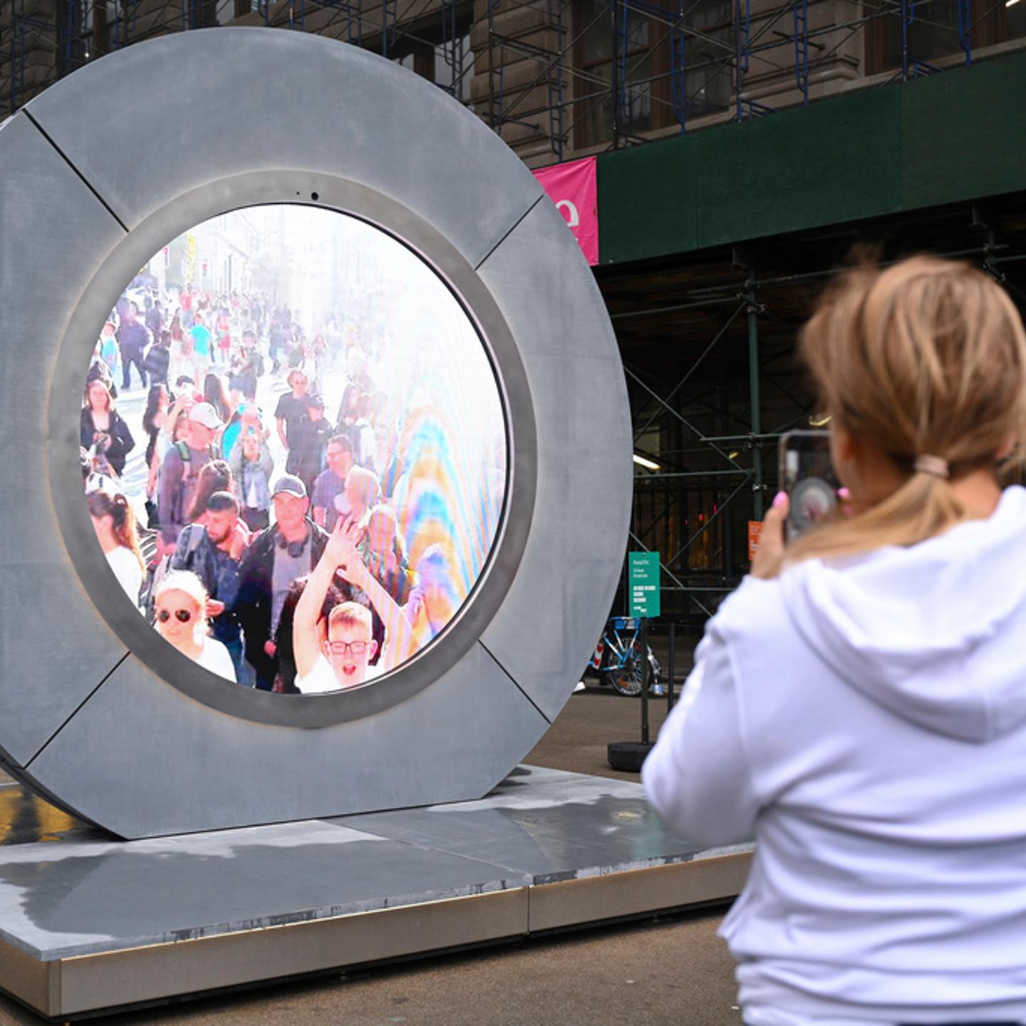 People interact with a livestream video "portal" in NYC