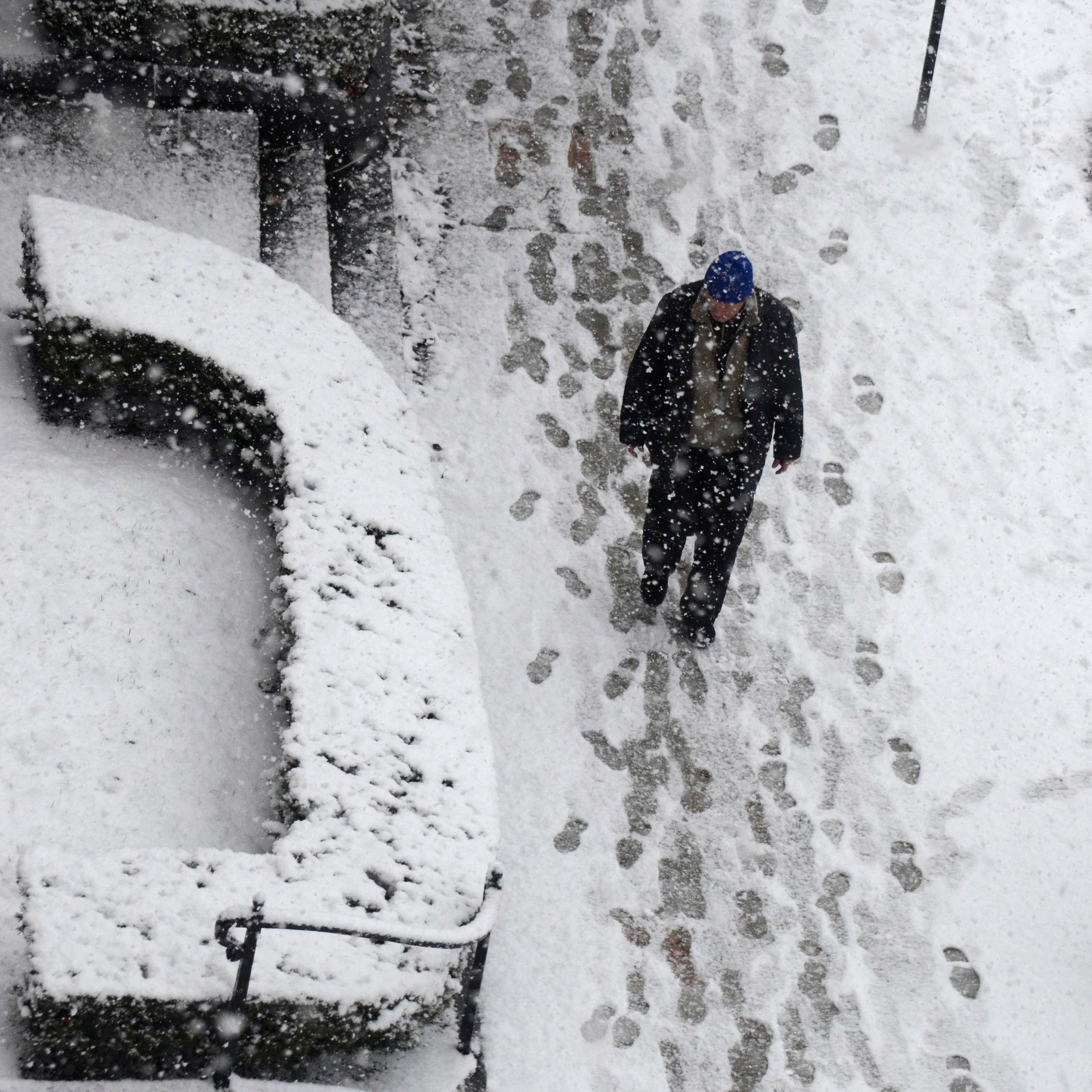 A man walks in snow in Pittsfield, Mass., as snow accumulates on the sidewalk on Dec. 10, 2014.