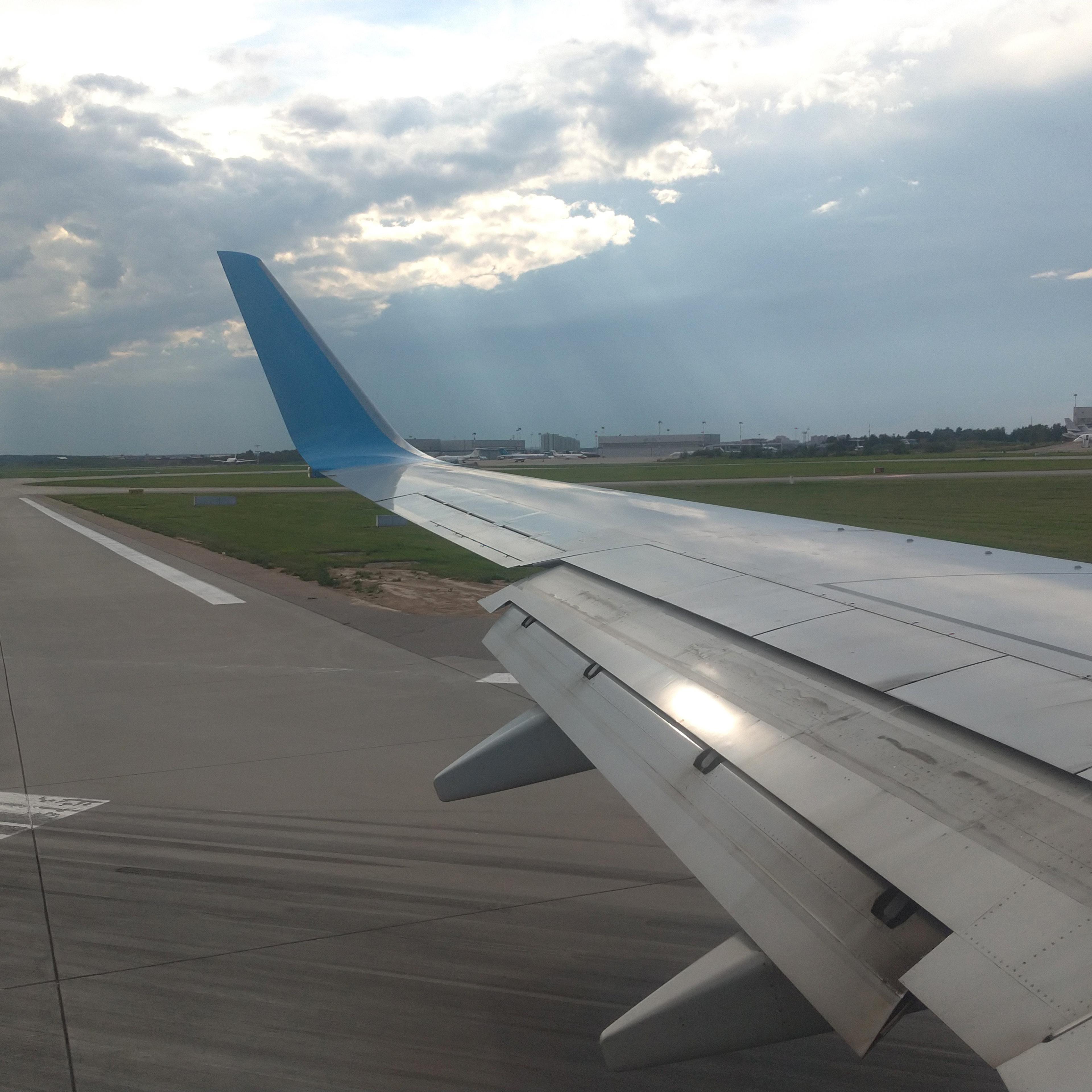 Airplane wing view out of the window on the cloudy sky The Earth background. Holiday vacation background. Wing of airplane flying above the clouds in the sky. Landing airplane, Moscow, Russia