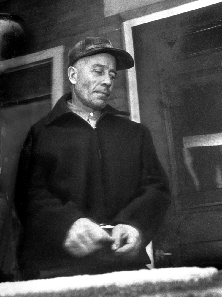 Killer Ed Gein, being led away from his house in handcuffs, Plainfield, Wis., 1957.