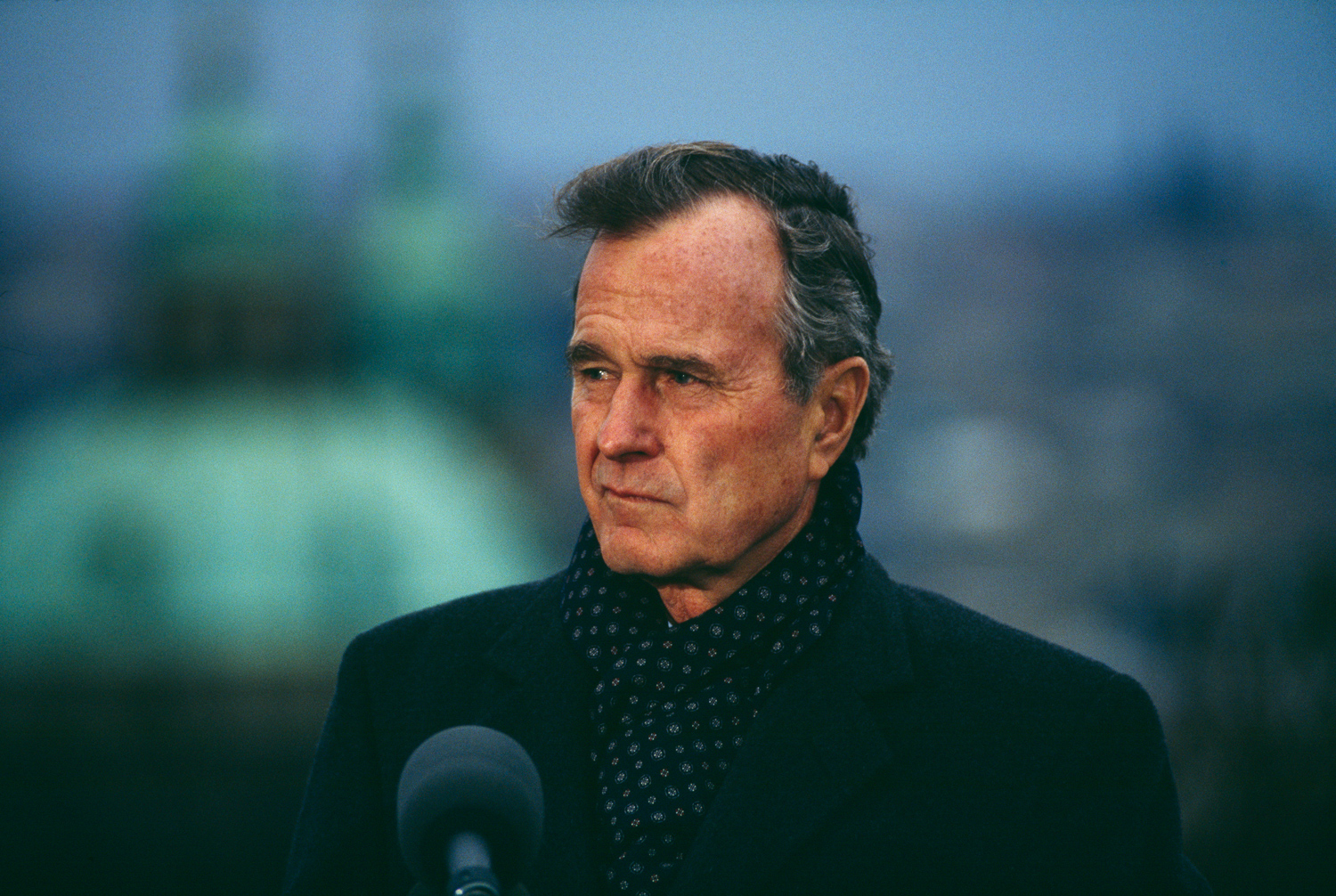 President George H.W. Bush bundled-up against autumn chill, speaking while visiting Prague, Czechoslovakia, November 18, 1990.	 