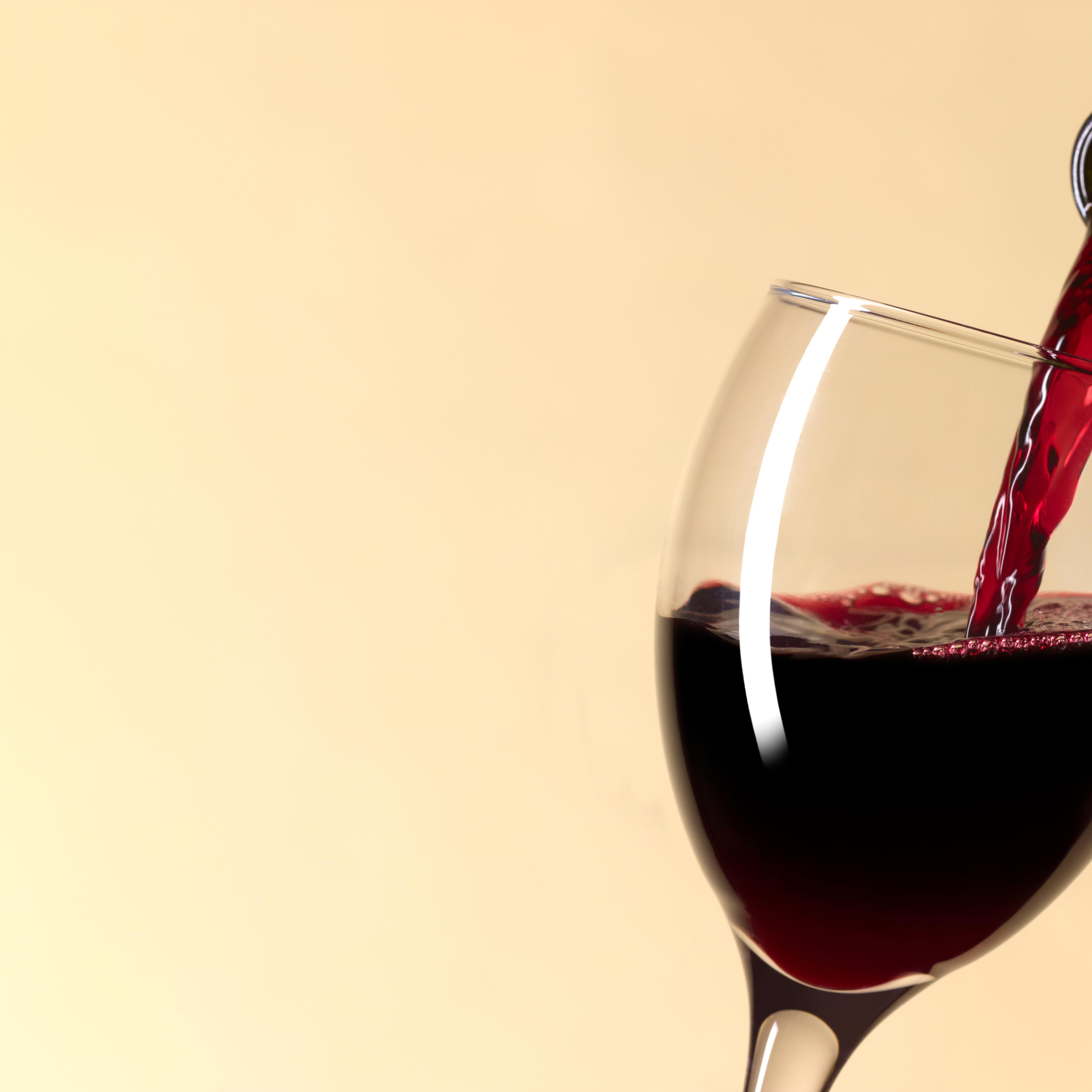 Pouring glass of red wine with copy space