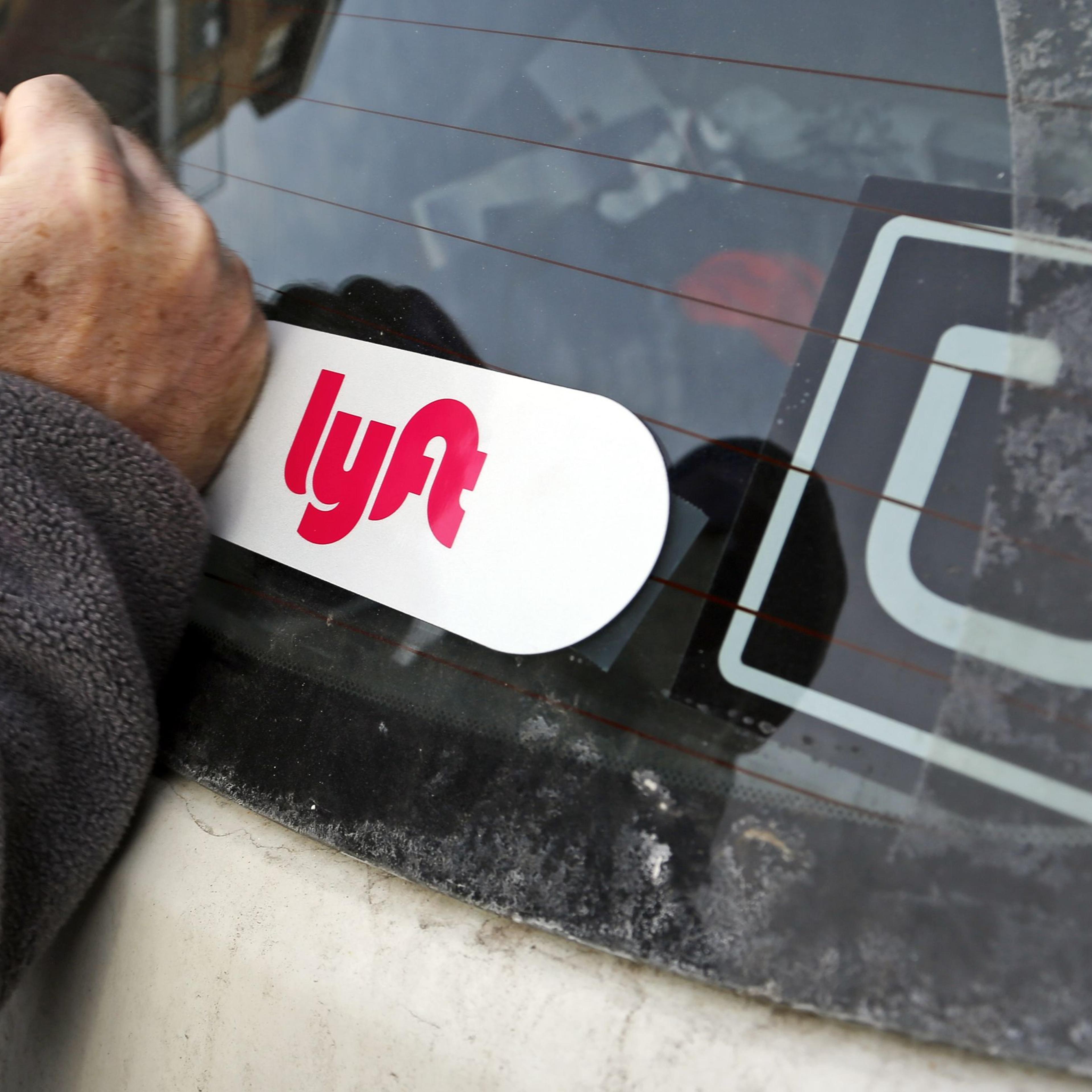 This is a Lyft logo being installed on a Lyft driver's car who also drives for Uber on in Pittsburgh, January 31, 2018.