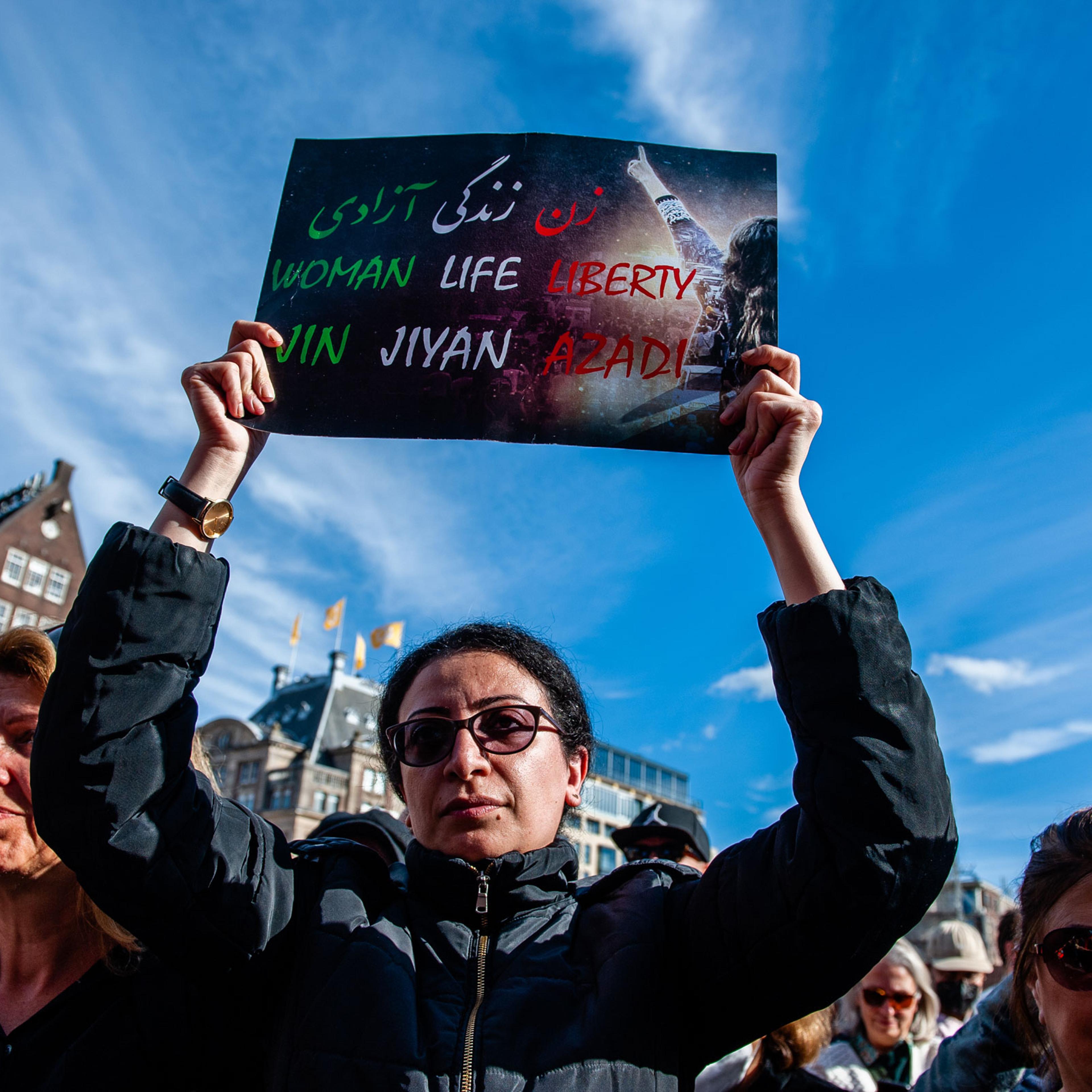 An Iranian woman is seen holding a placard with the three words that have become a symbol of protests, in Amsterdam on Oct. 16, 2022.