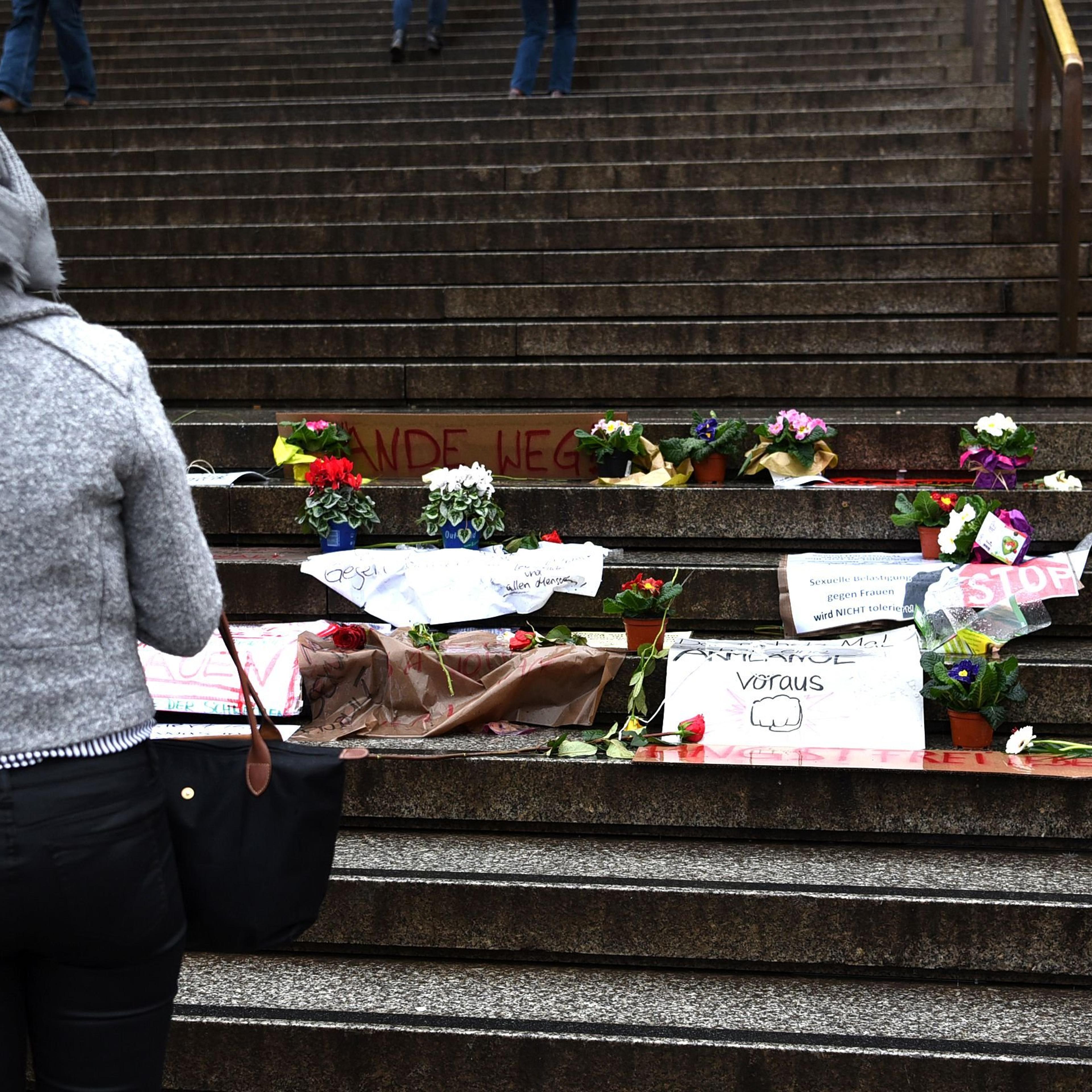 A woman looks at flowers and letters of protest that are laid down on the steps in front of the Cologne main train station in Cologne, western Germany on Jan. 11, 2016.