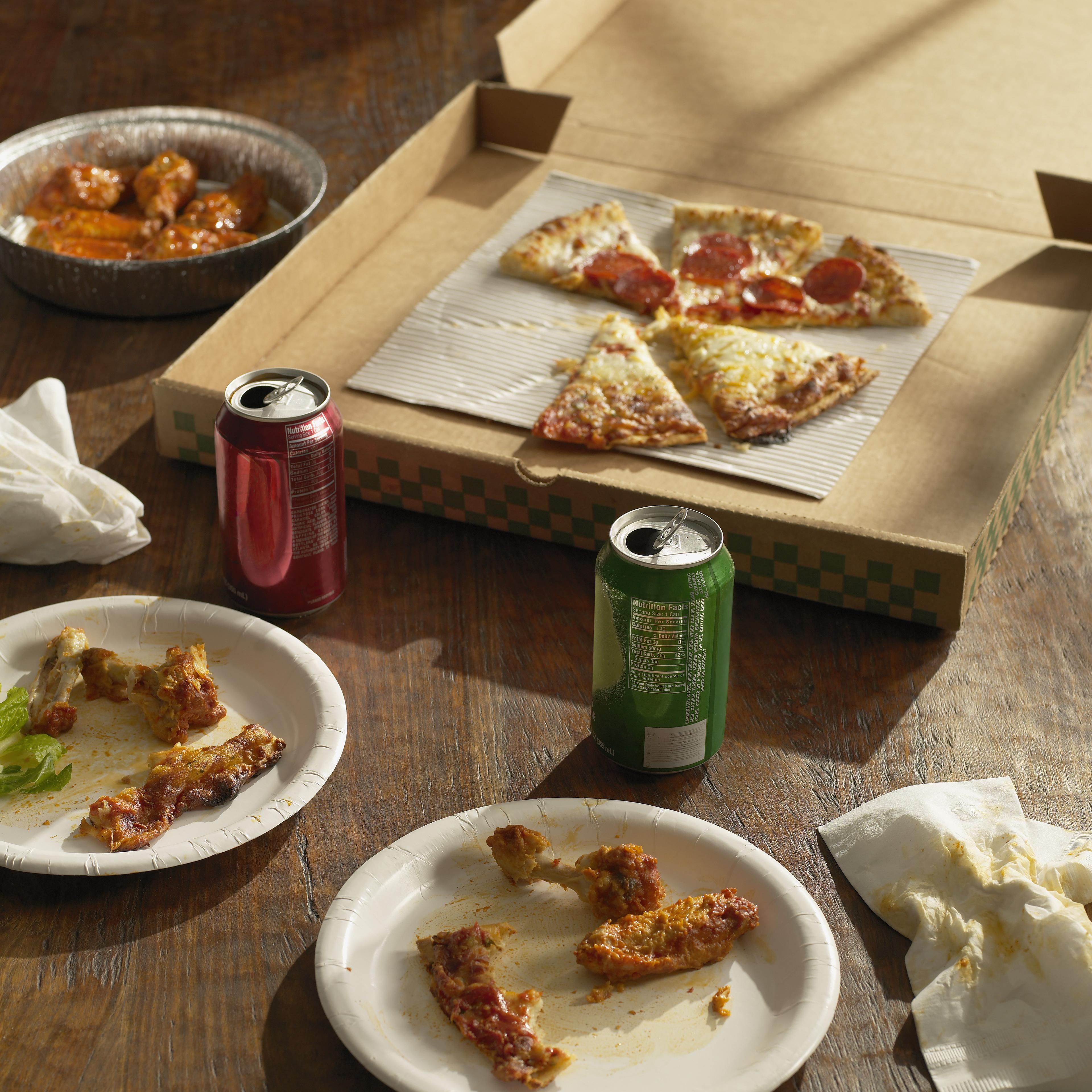 Half-eaten pizza , Buffalo wings and sodas