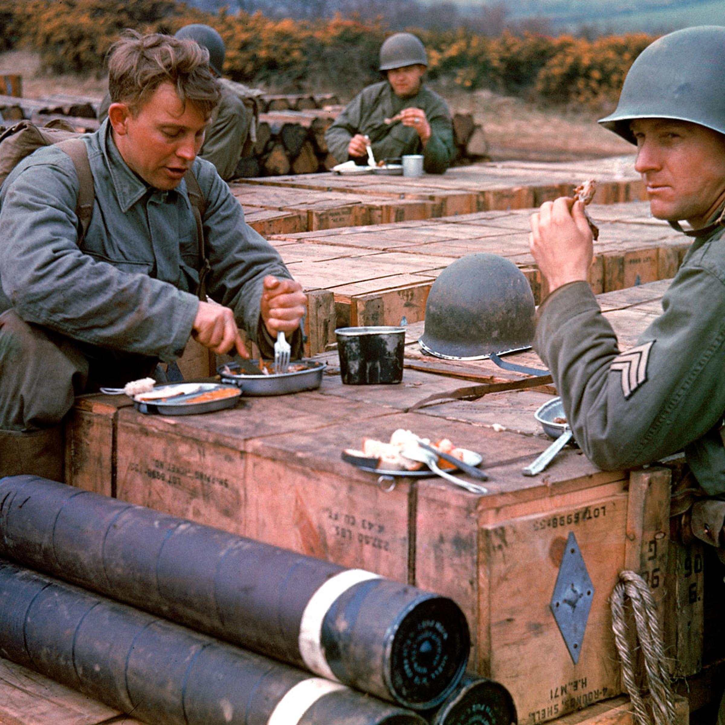 American combat engineers eat a meal atop boxes of ammunition stockpiled for the impending D-Day invasion, May 1944.