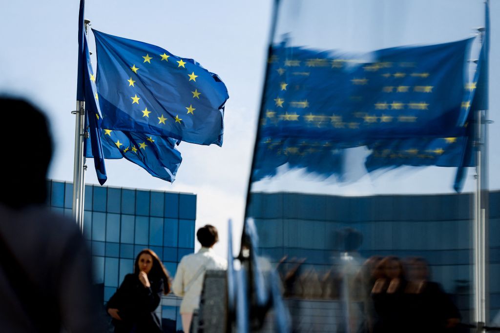 People walk in front of the European Union flag in Brussels on Sept. 23, 2021.