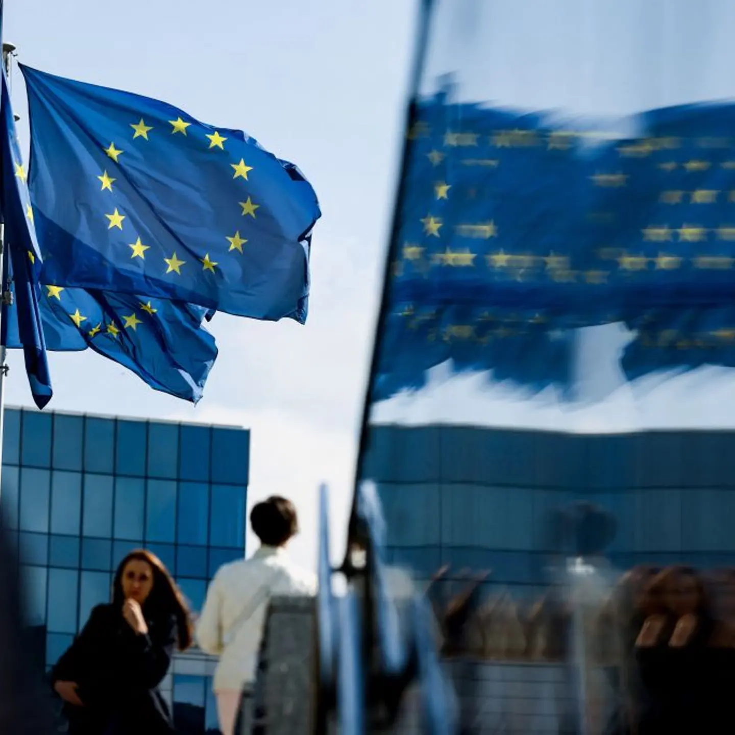 People walk in front of the European Union flag in Brussels on Sept. 23, 2021.