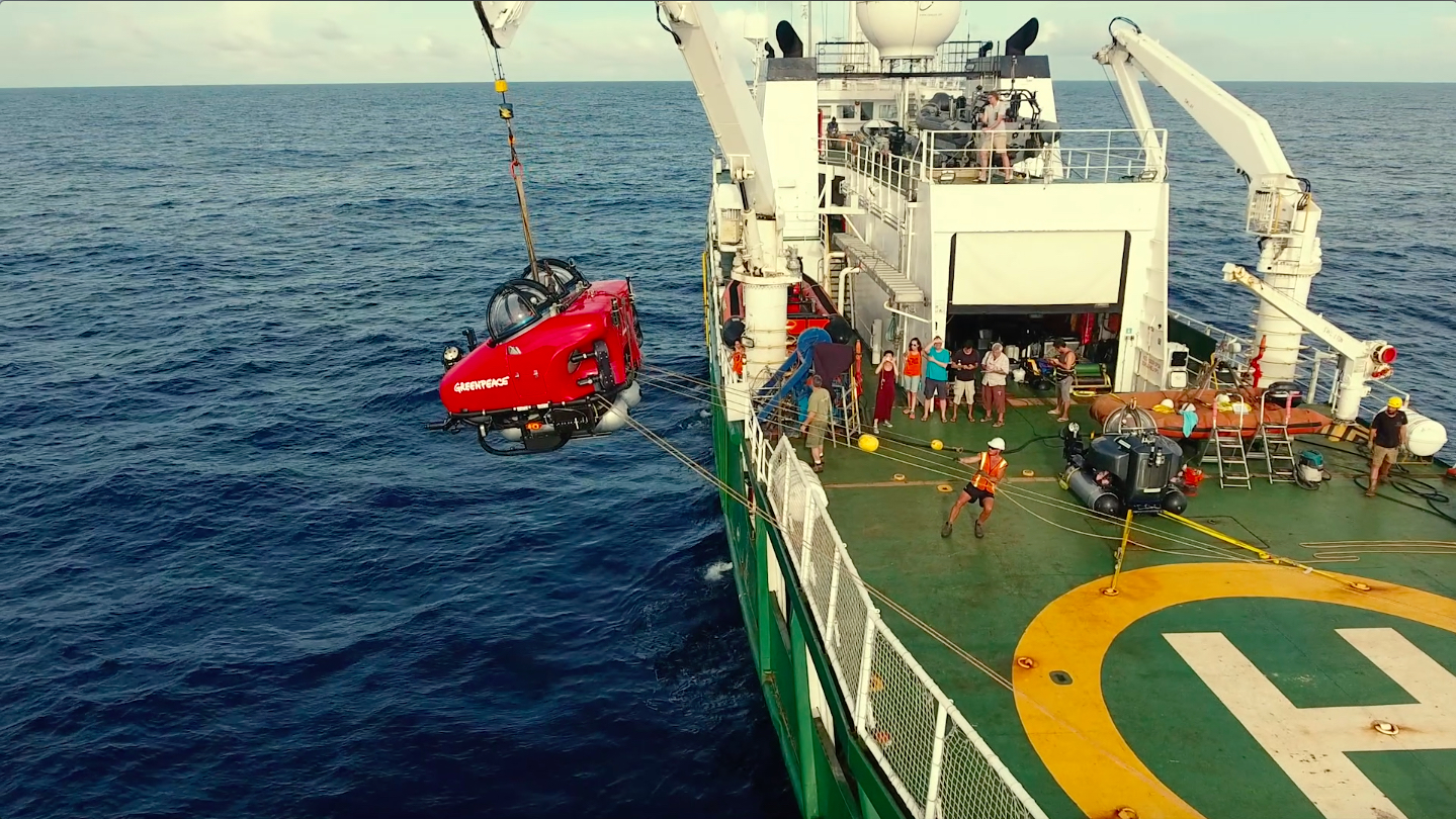 A submarine is hoisted into the air before being lowered into the water.