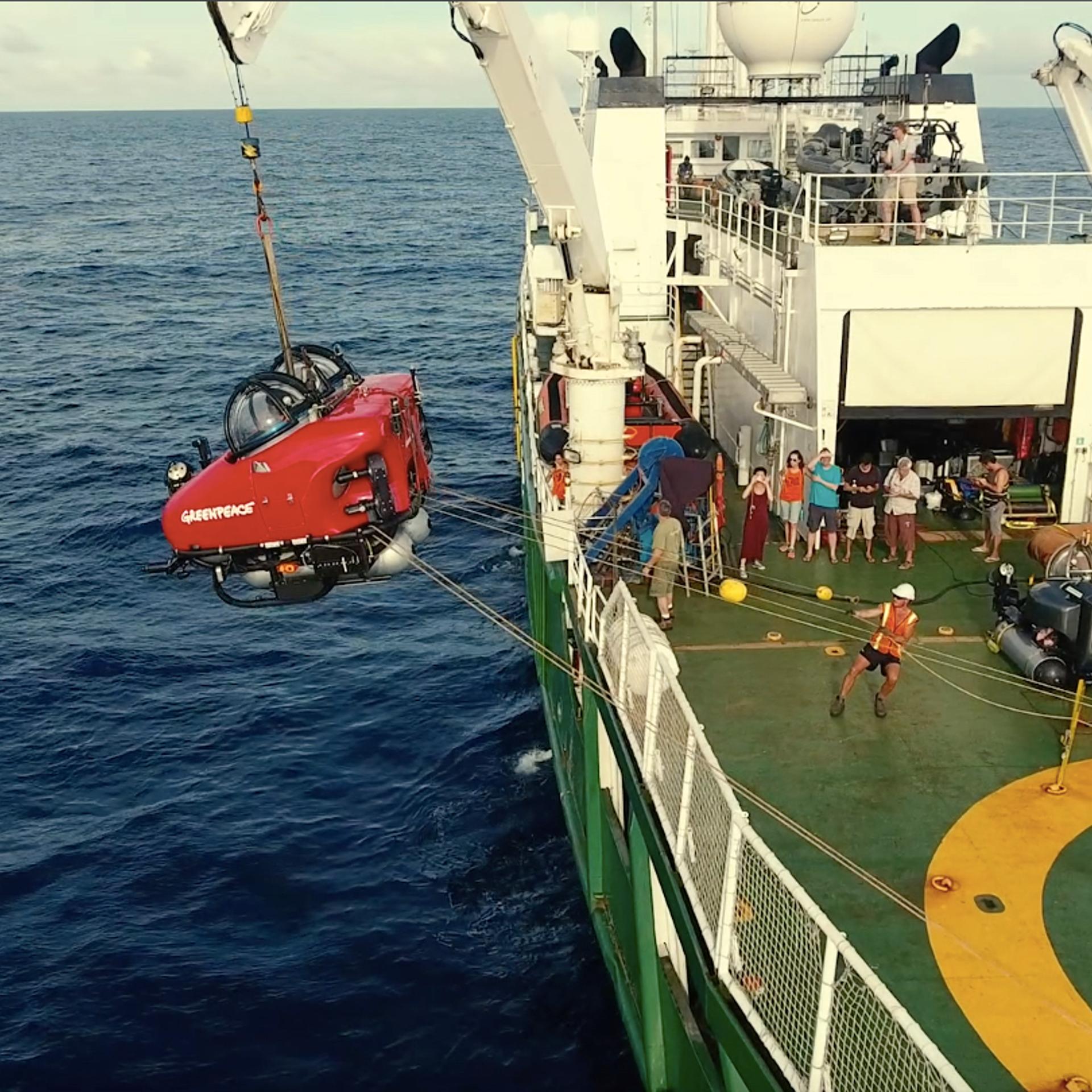 A submarine is hoisted into the air before being lowered into the water.