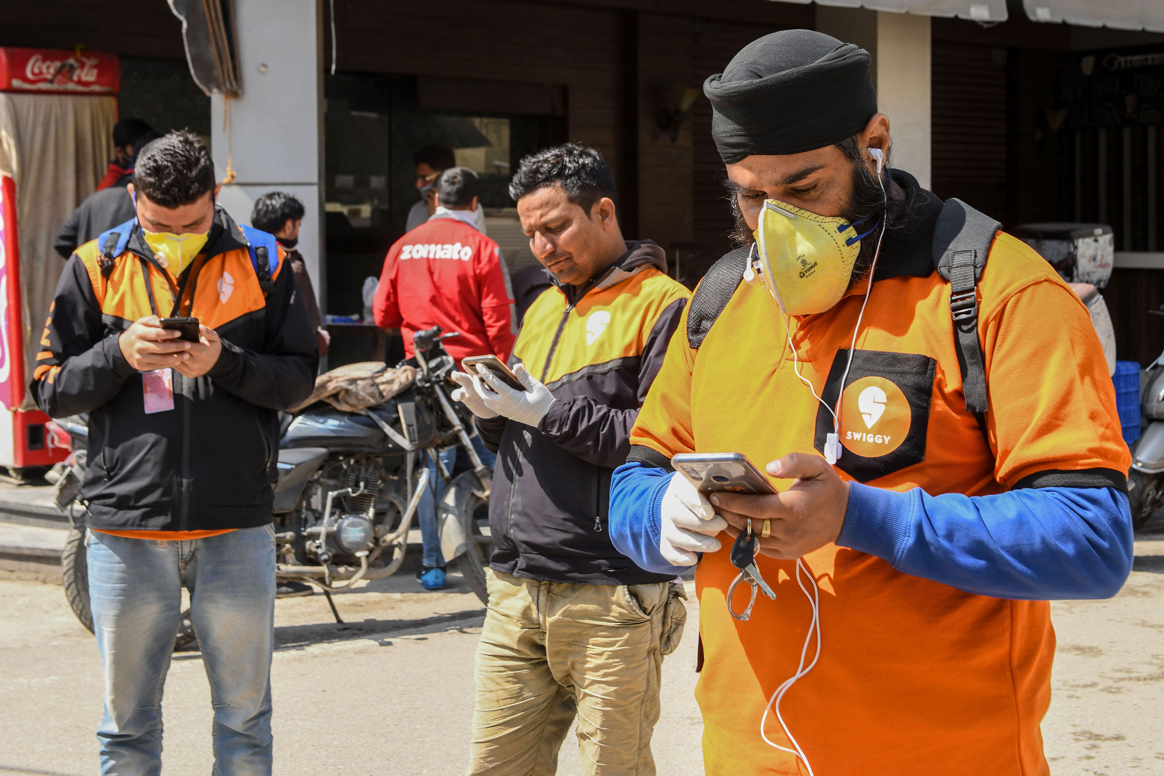 Swiggy delivery workers their mobile phones  in Amritsar, India on March 28, 2020.