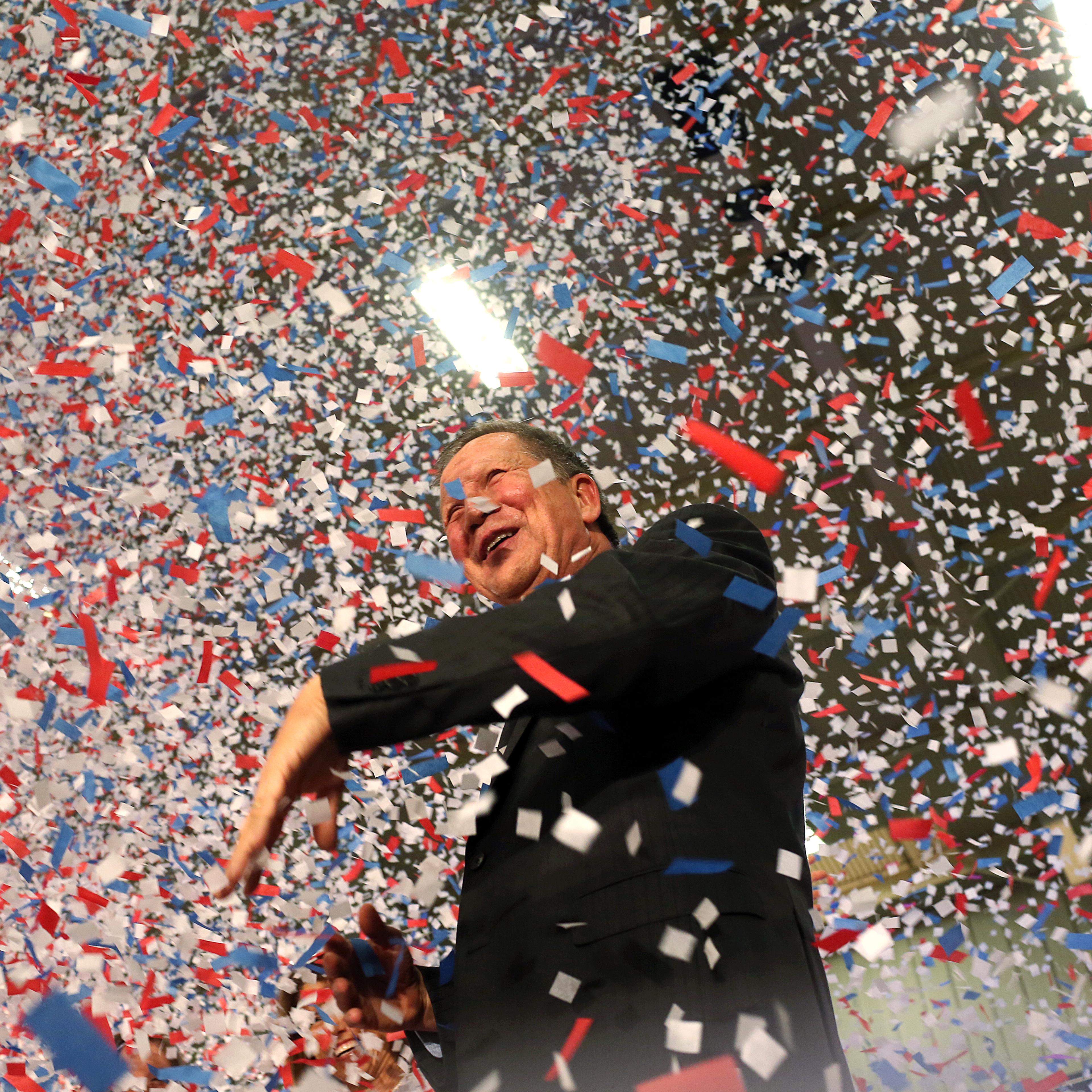 Republican presidential candidate, Ohio Gov. John Kasich waves confetti out of his way after giving his victory speech at Baldwin-Wallace University in Berea, Ohio on March 15, 2016.