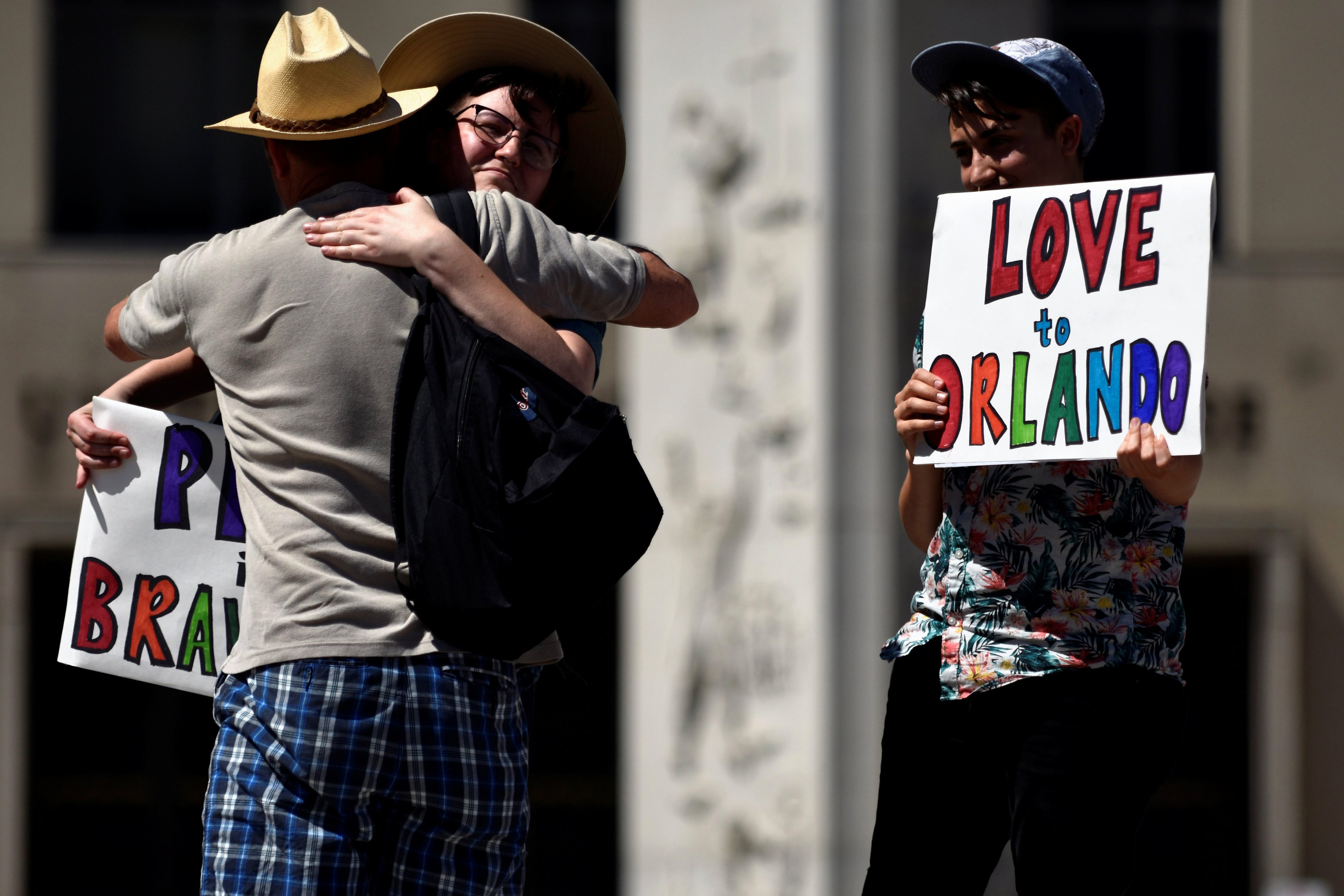 An attendee of the Capital Pride Festival hugs Nick Wilson as Ciaran Lithgow holds a sign of condolence for victims of the attack on a gay nightclub in Orlando, Fla. in Washington on June 12, 2016.