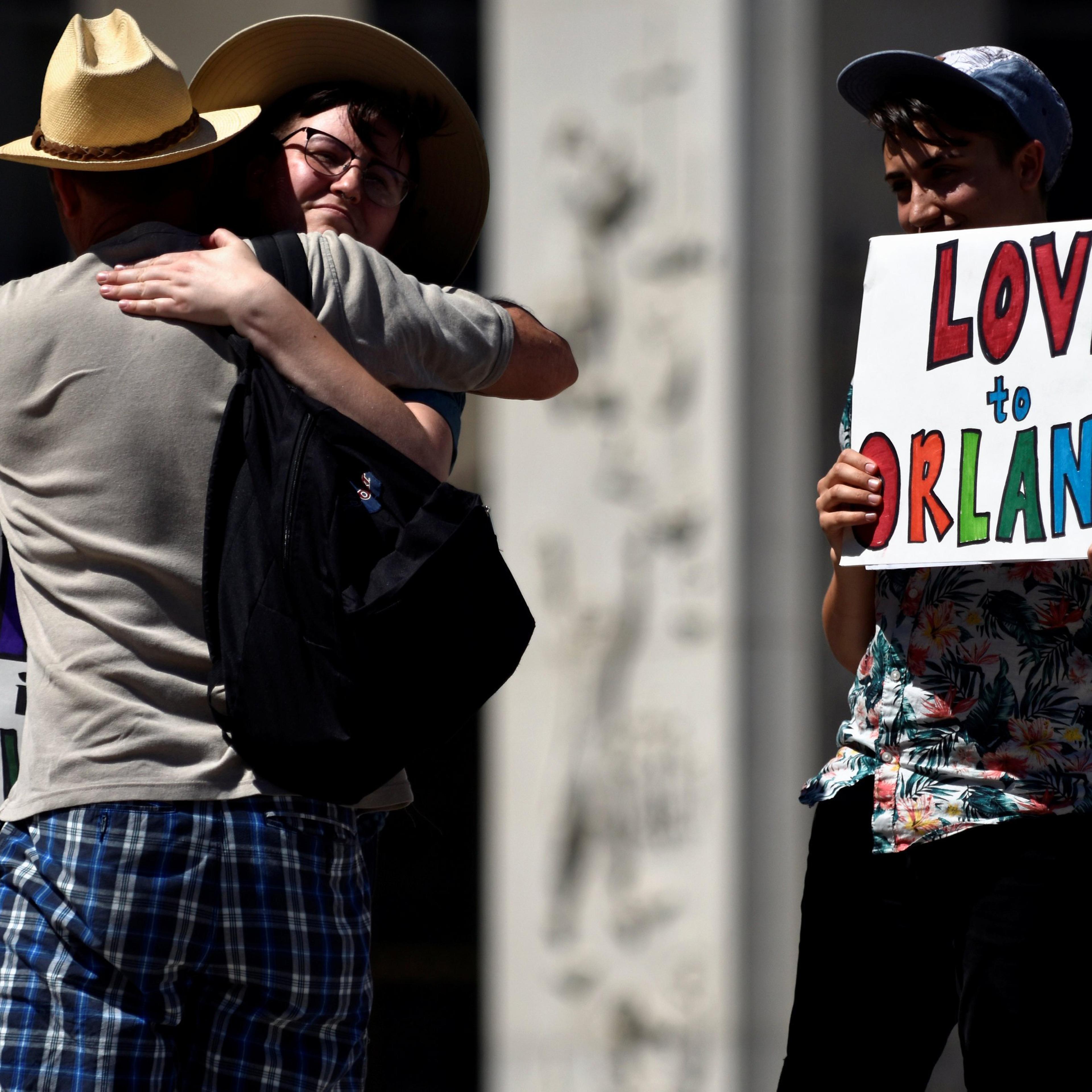An attendee of the Capital Pride Festival hugs Nick Wilson as Ciaran Lithgow holds a sign of condolence for victims of the attack on a gay nightclub in Orlando, Fla. in Washington on June 12, 2016.