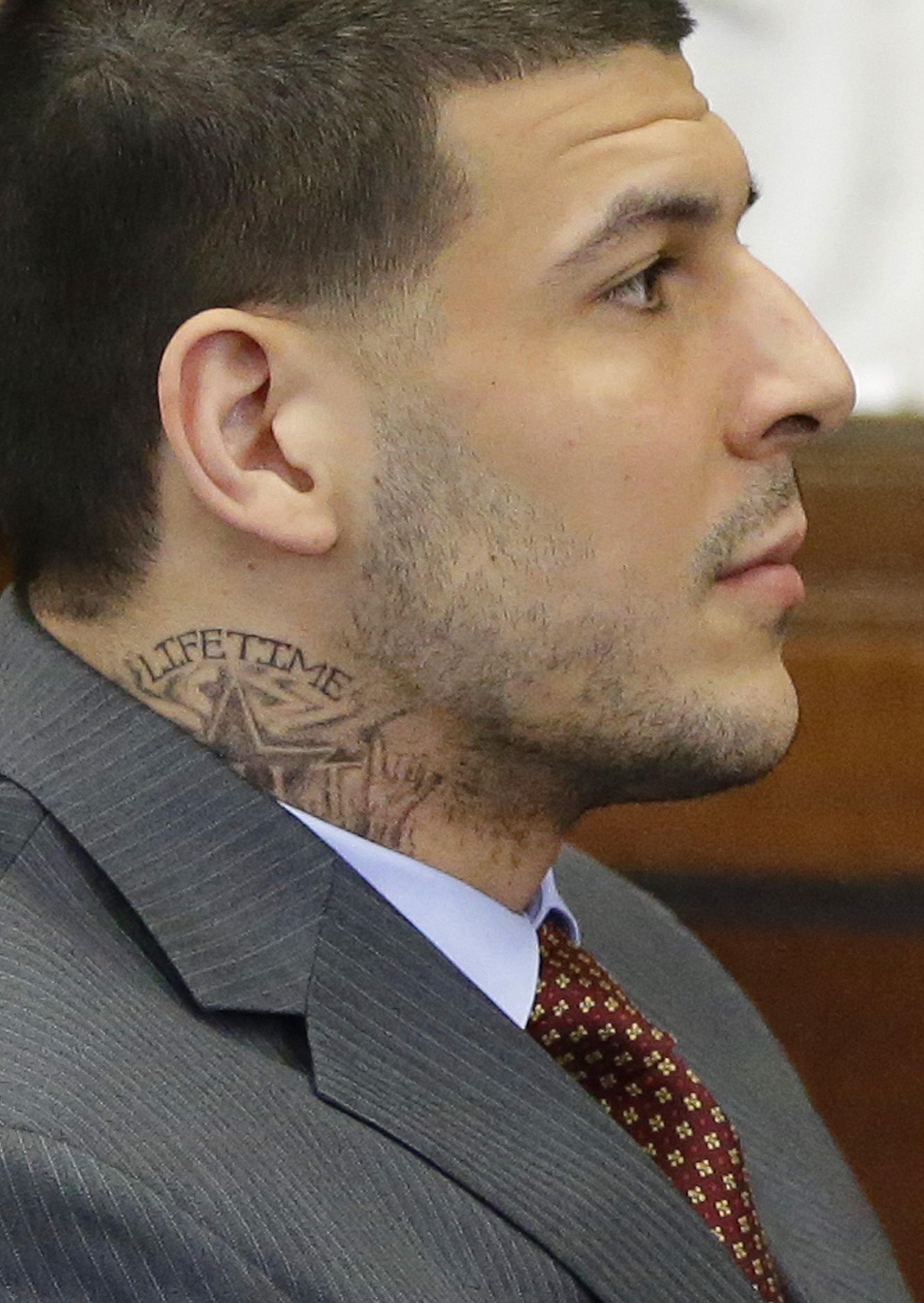 Sporting a new neck tattoo, former New England Patriots NFL football player Aaron Hernandez sits at the defense table during his arraignment on a charge of trying to silence a witness in a double murder case against him by shooting the man in the face at