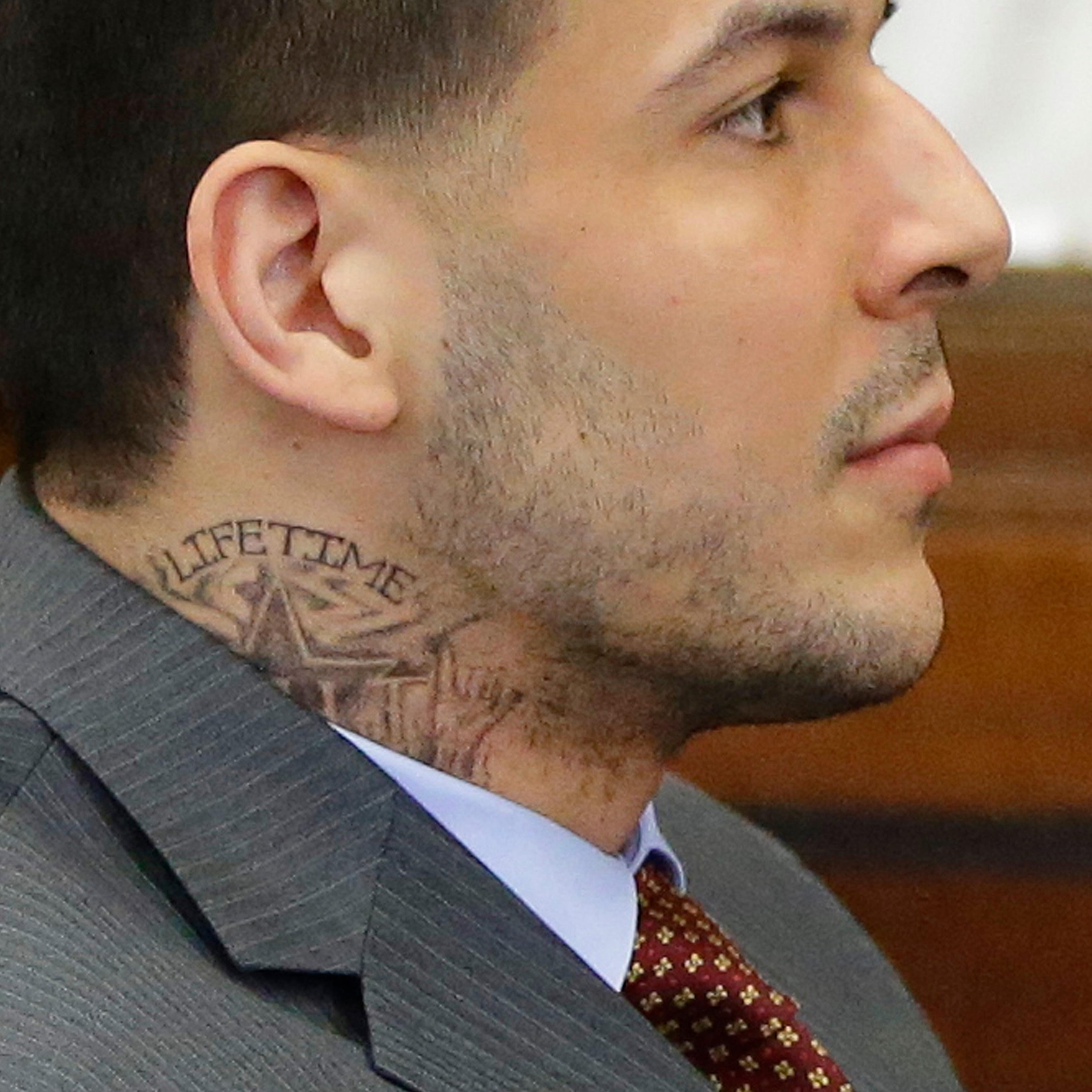 Sporting a new neck tattoo, former New England Patriots NFL football player Aaron Hernandez sits at the defense table during his arraignment on a charge of trying to silence a witness in a double murder case against him by shooting the man in the face at