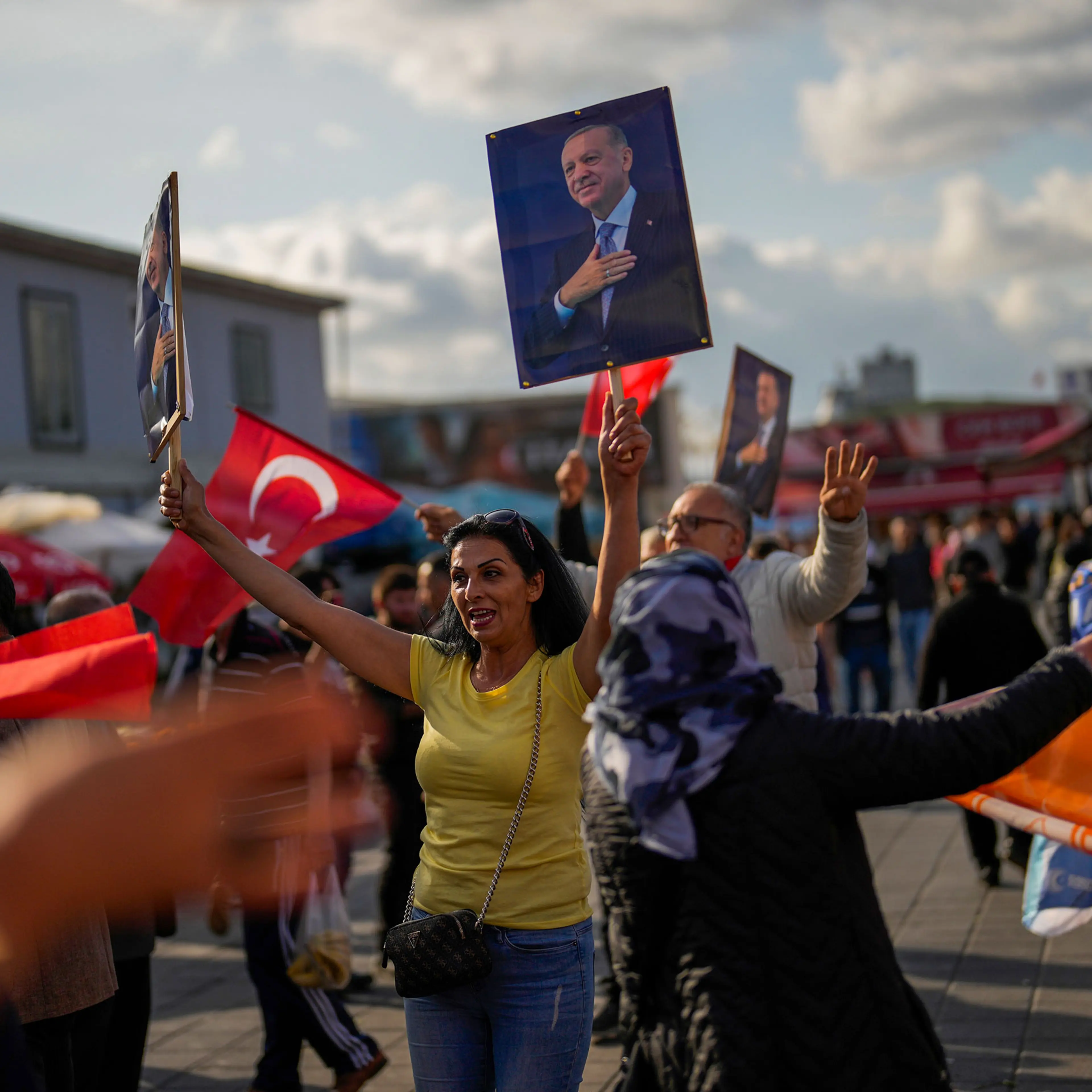 Supporters of Turkish President and People’s Alliance’s presidential candidate Recep Tayyip Erdogan dance as they give handouts to commuters in Istanbul