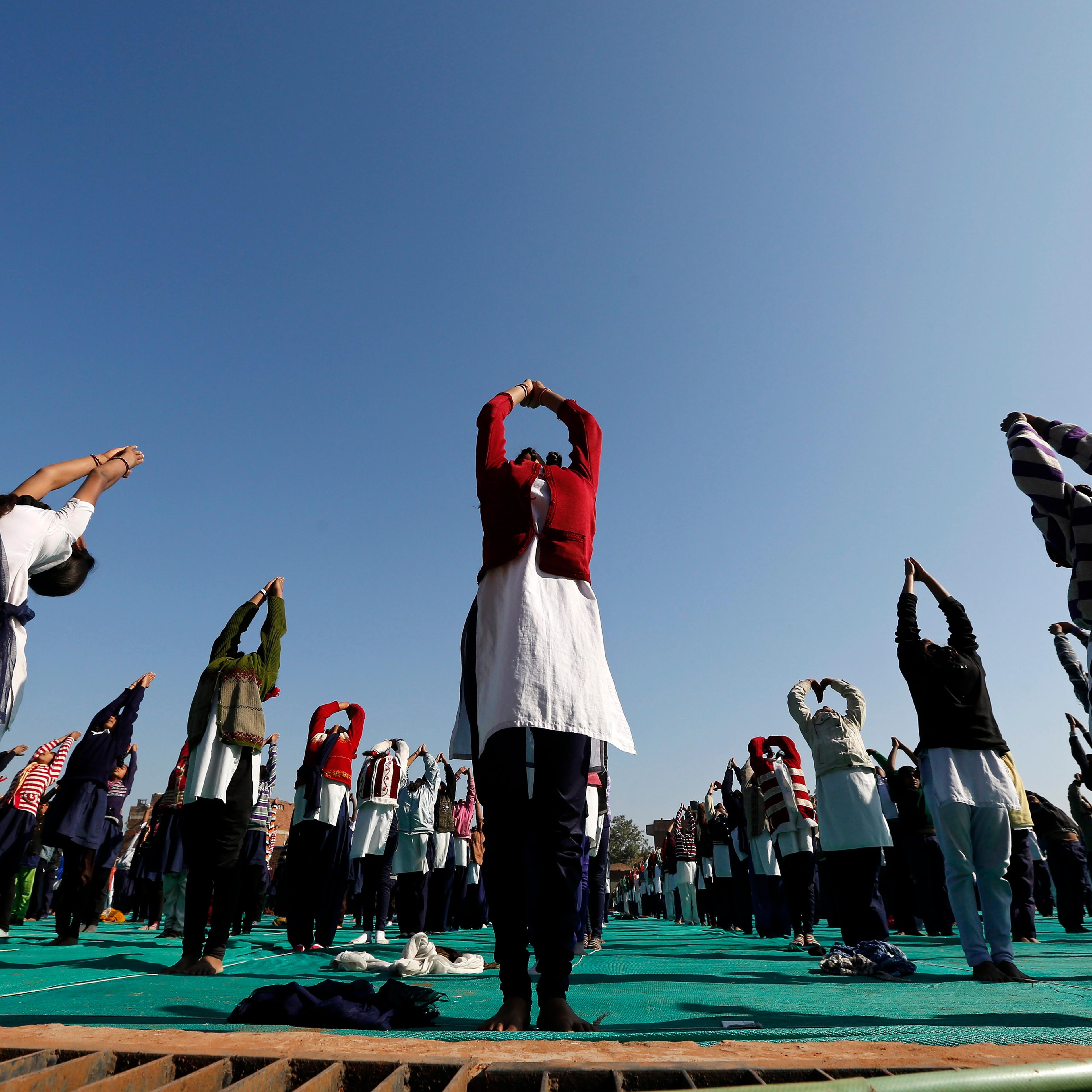 Schoolchildren offer prayers to Sun god during a yoga session at a camp in Ahmedabad