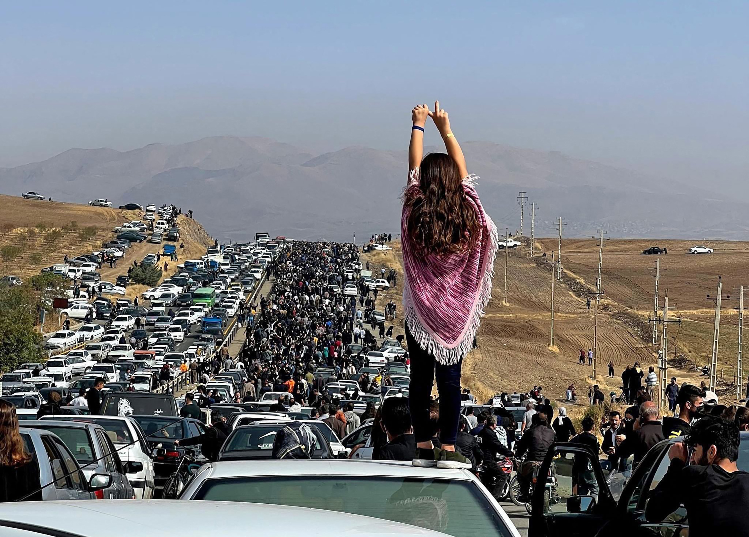 An unveiled woman standing on top of a vehicle as thousands make their way towards Aichi cemetery in Saqez, Mahsa Amini's home town in the western Iranian province of Kurdistan, to mark 40 days since her death, defying heightened security measures as part of a bloody crackdown on women-led protests. 