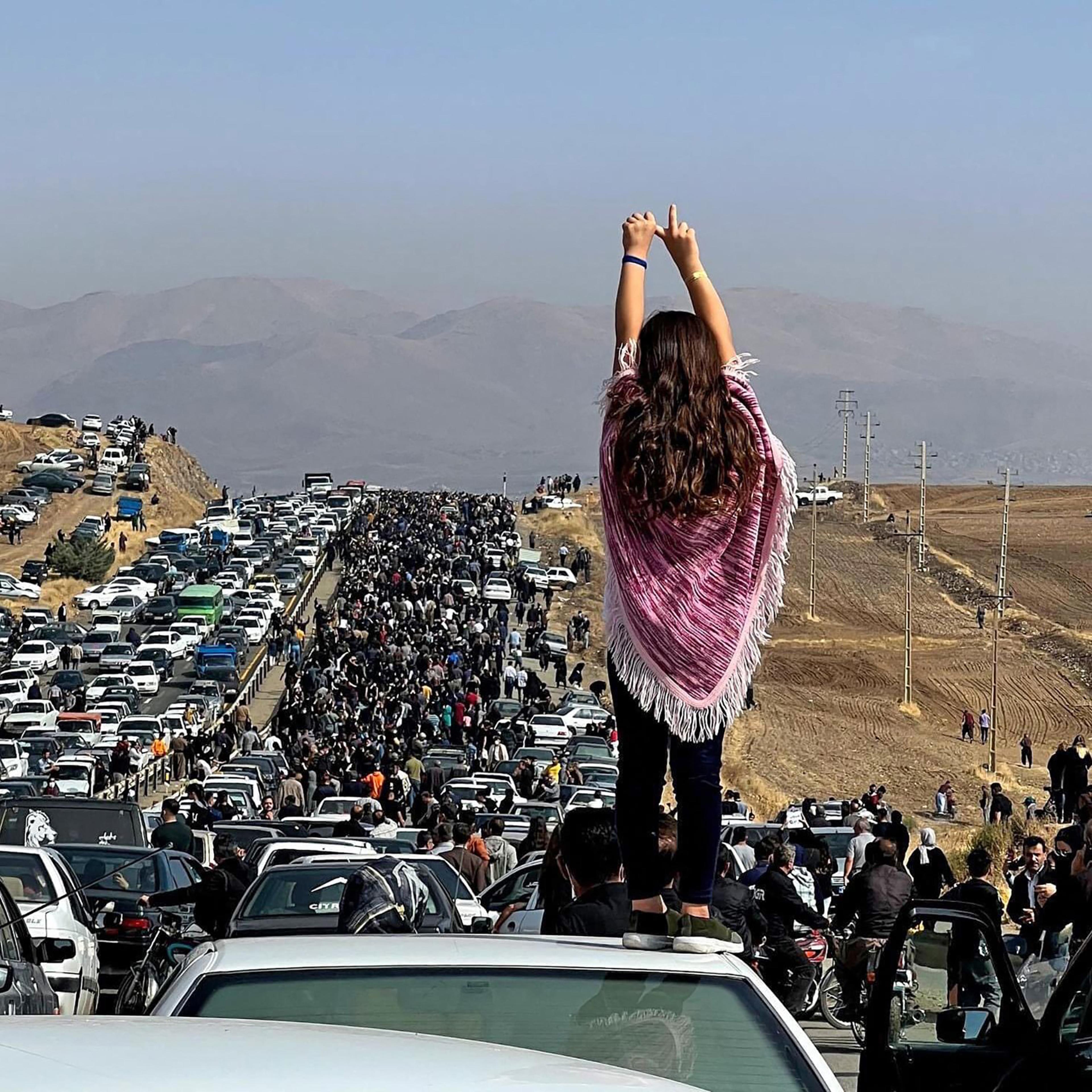 An unveiled woman standing on top of a vehicle as thousands make their way towards Aichi cemetery in Saqez, Mahsa Amini's home town in the western Iranian province of Kurdistan, to mark 40 days since her death, defying heightened security measures as part of a bloody crackdown on women-led protests.