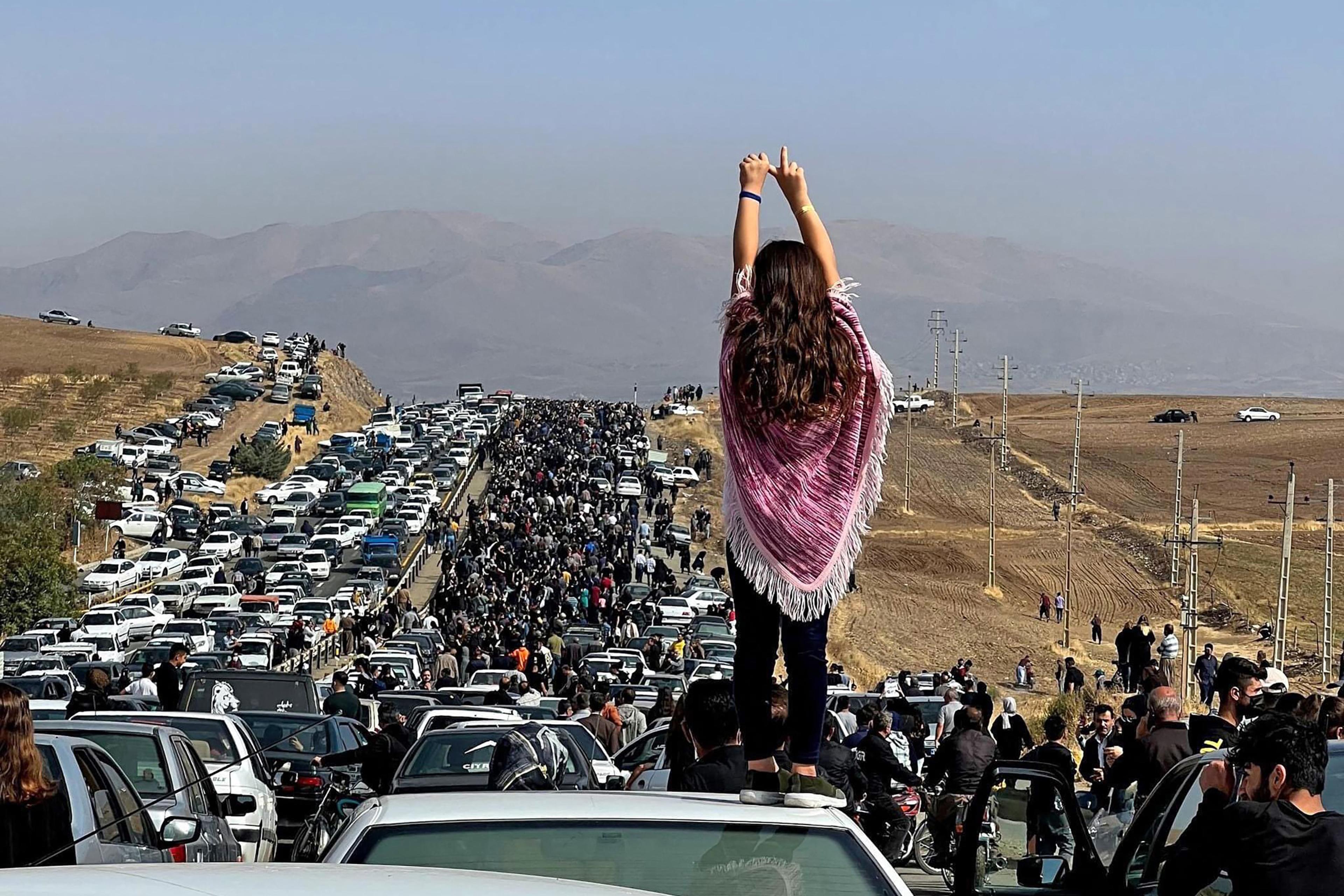An unveiled woman standing on top of a vehicle as thousands make their way towards Aichi cemetery in Saqez, Mahsa Amini's home town in the western Iranian province of Kurdistan, to mark 40 days since her death, defying heightened security measures as part of a bloody crackdown on women-led protests.