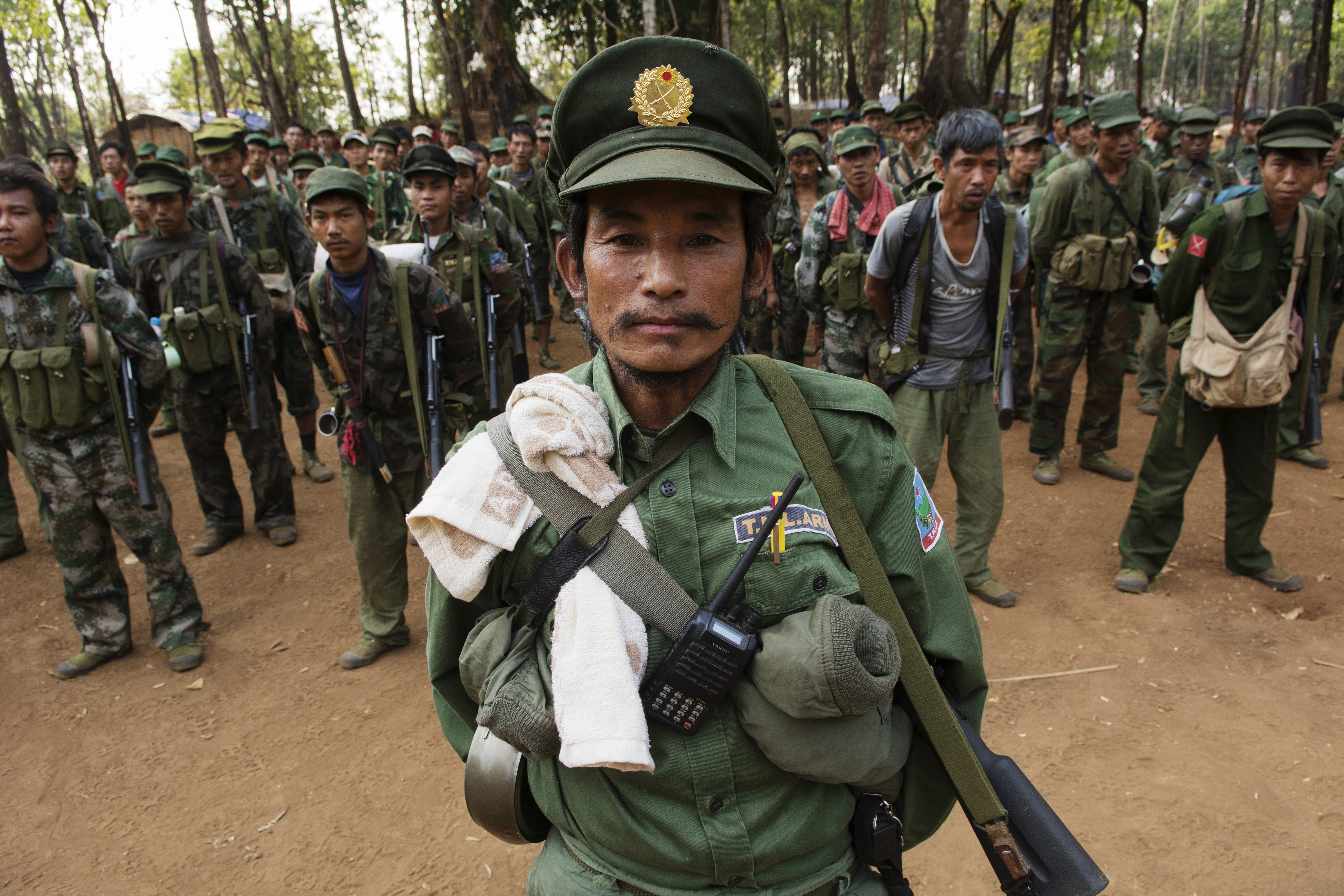 SHAN STATE, MYANMAR - 2014/03/12: An officer from the TNLA (Ta'ang National Liberation Army, Ta'ang is another word for Palaung) stands at attention with his soldiers during a morning gathering in a military camp.The TNLA, created in 2009, claims about 1
