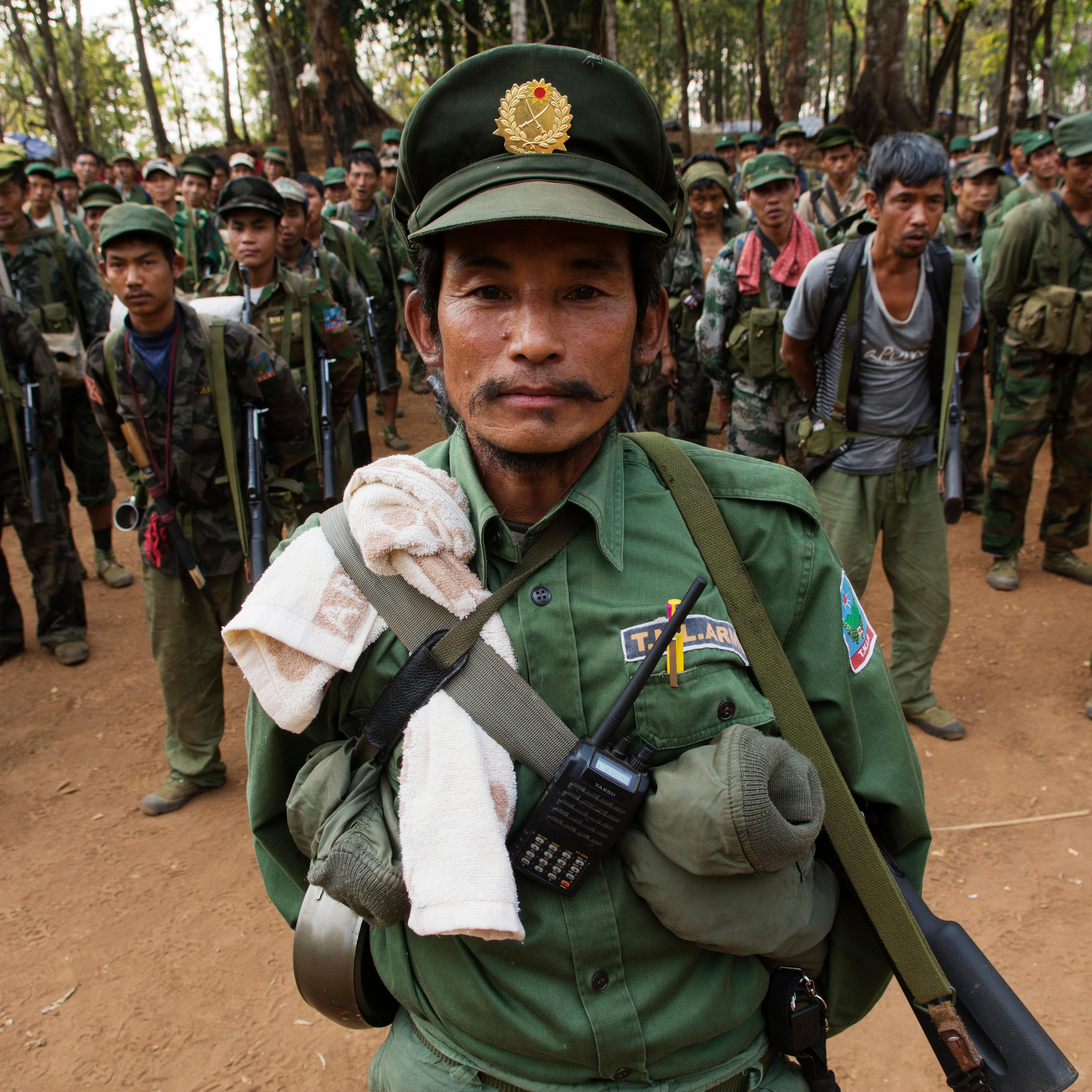 SHAN STATE, MYANMAR - 2014/03/12: An officer from the TNLA (Ta'ang National Liberation Army, Ta'ang is another word for Palaung) stands at attention with his soldiers during a morning gathering in a military camp.The TNLA, created in 2009, claims about 1