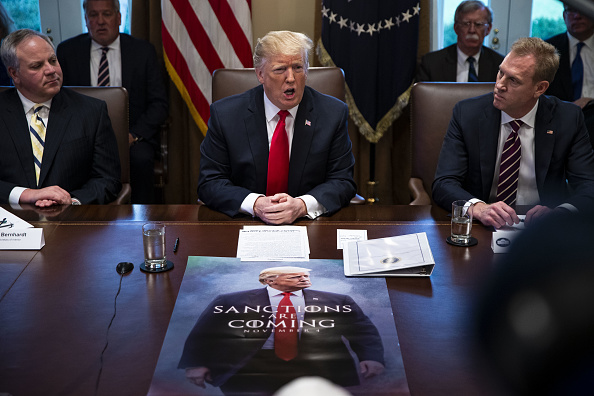 U.S. President Donald Trump, center, speaks in front of a poster that reads 'Sanctions Are Coming' during a meeting in the Cabinet Room of the White House in Washington, D.C., U.S., on on Wednesday, Jan. 2, 2019.