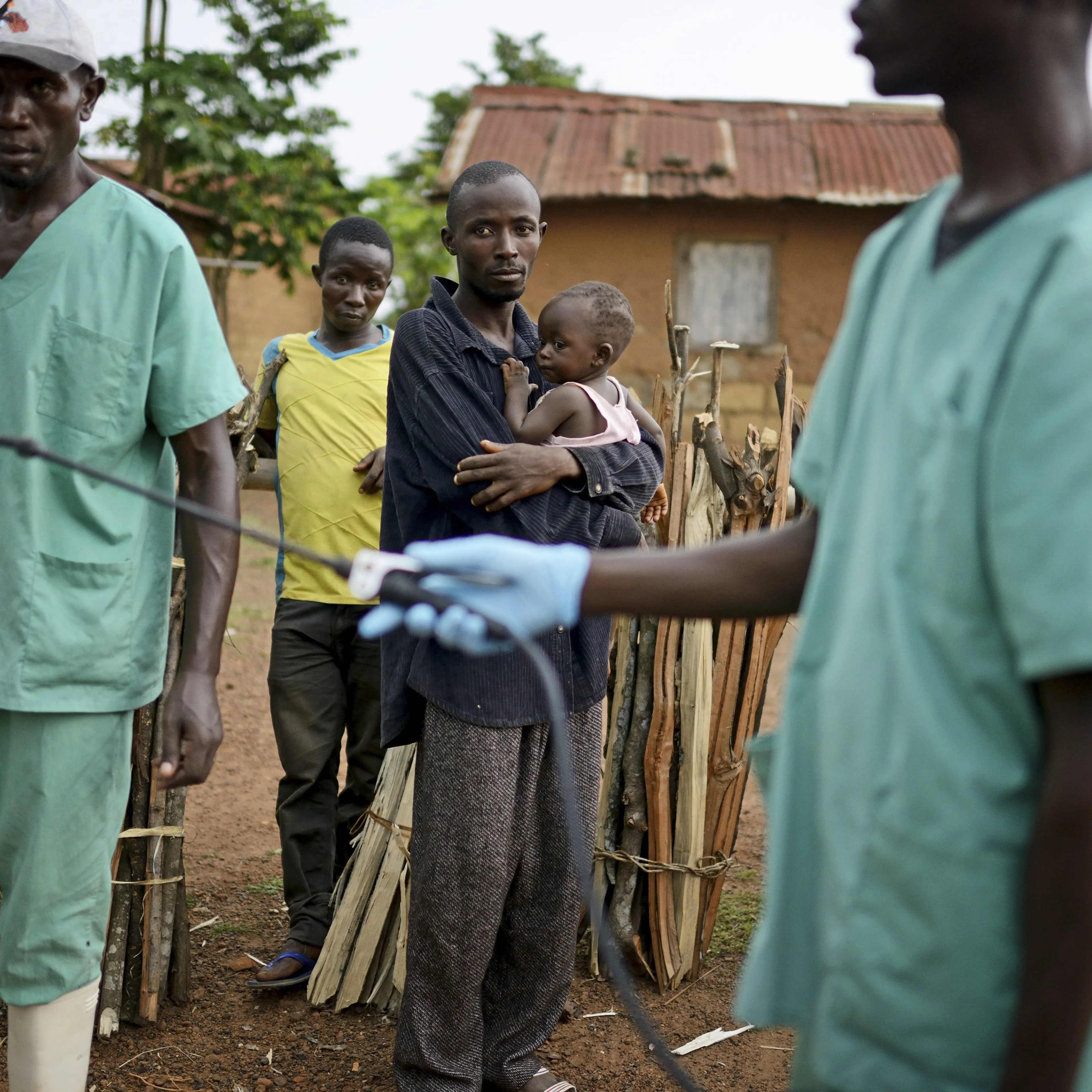 Locals watch workers with Doctors Without Borders as they disinfect after leaving a private clinic working to combat the spread of the Ebola virus in Teldou, Guinea, July 10, 2014.
