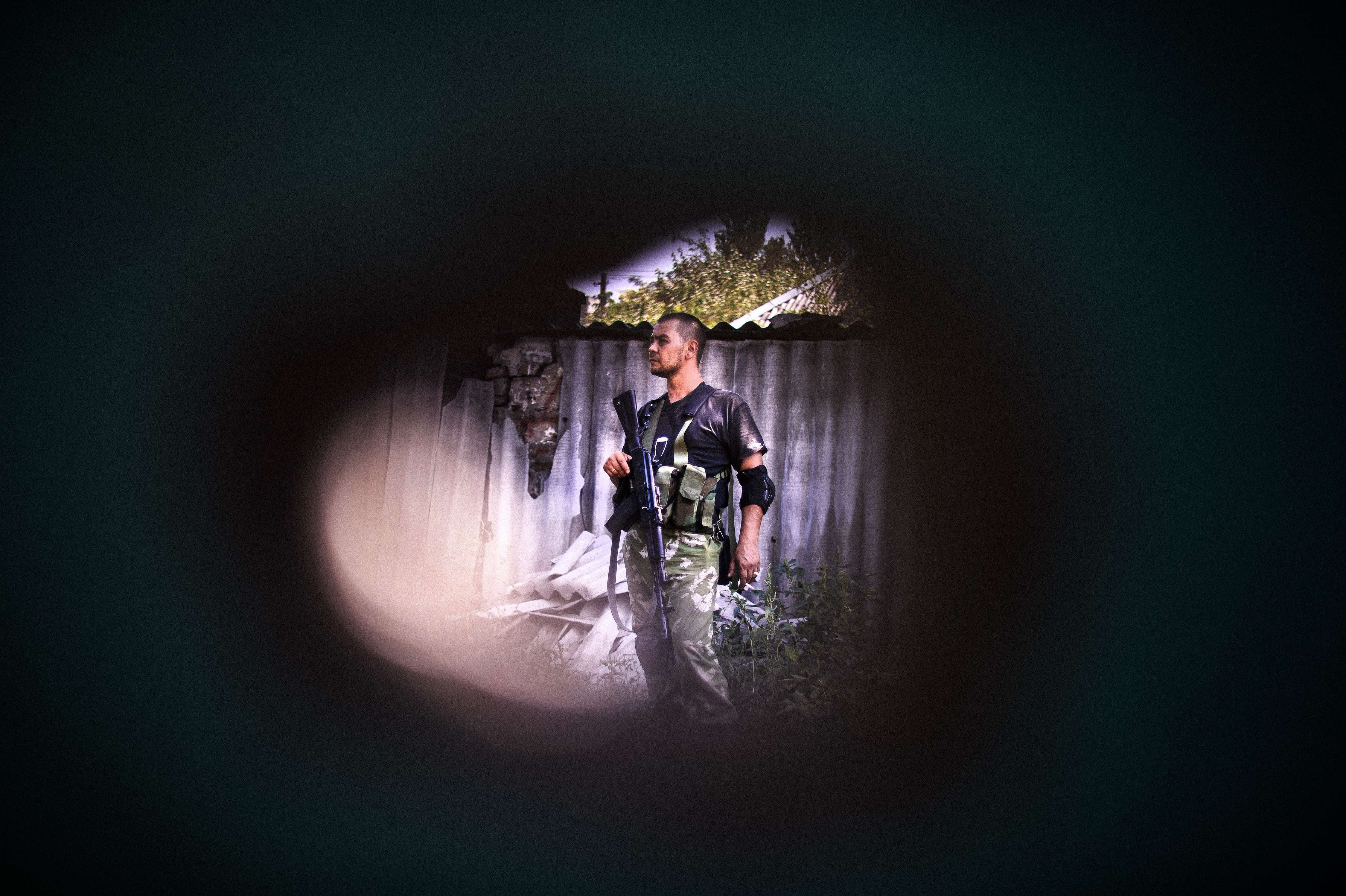 A pro-Russian gunman is seen through a shrapnel hole after shelling in Donetsk on August 22, 2014.