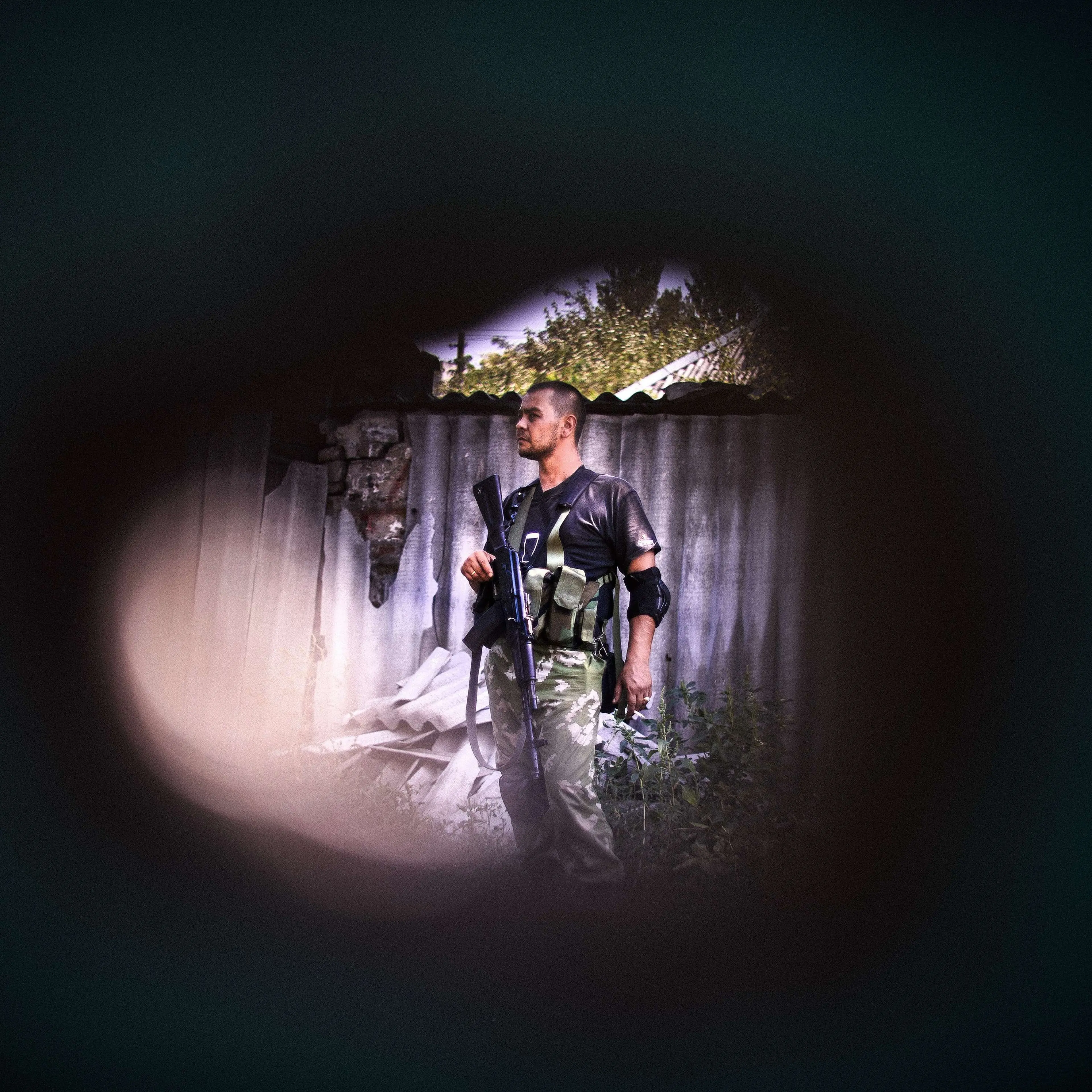A pro-Russian gunman is seen through a shrapnel hole after shelling in Donetsk on August 22, 2014.