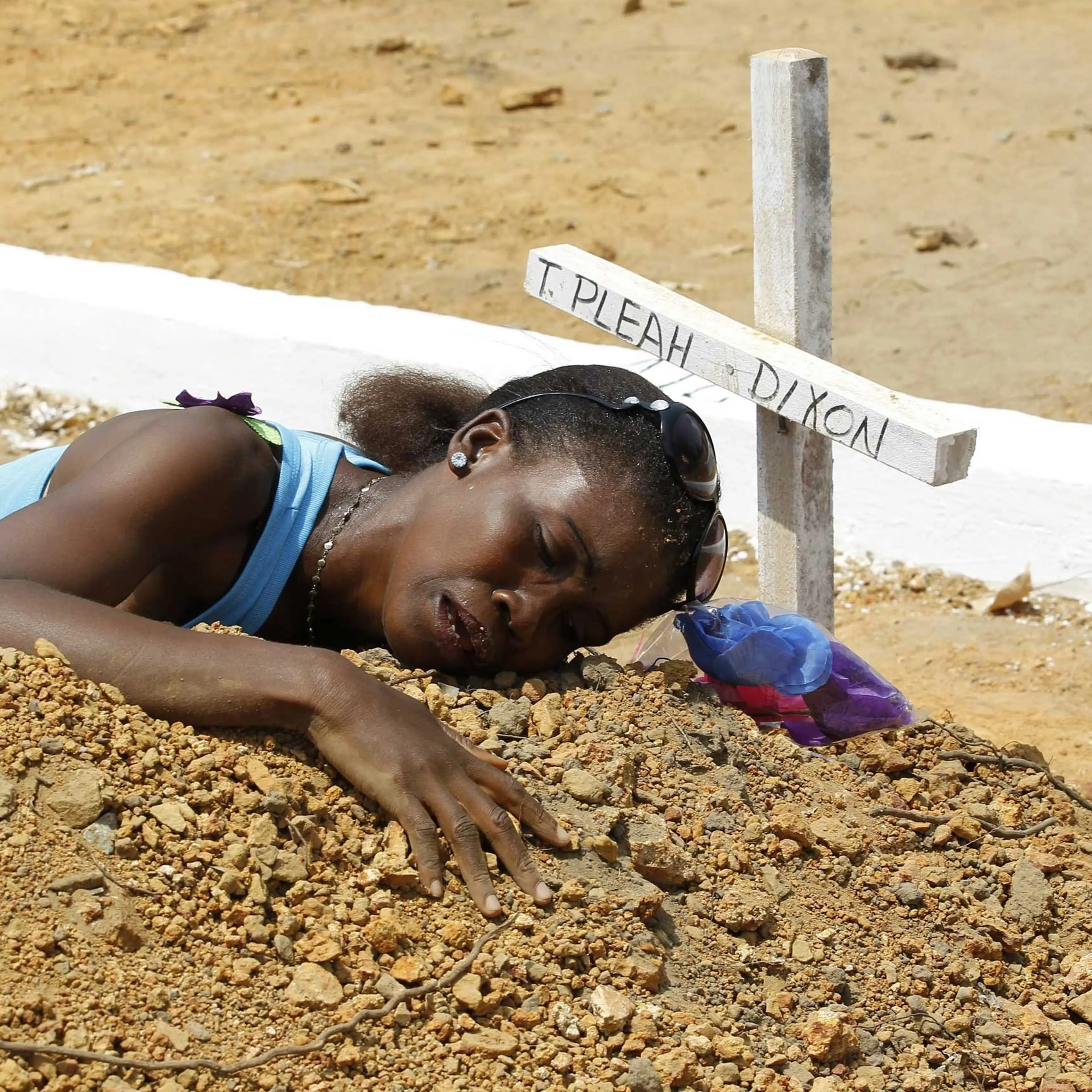 A woman mourns at the grave of her late brother at the National Cemetry on Disco Hill, Margibi County, Liberia, March 11, 2015.