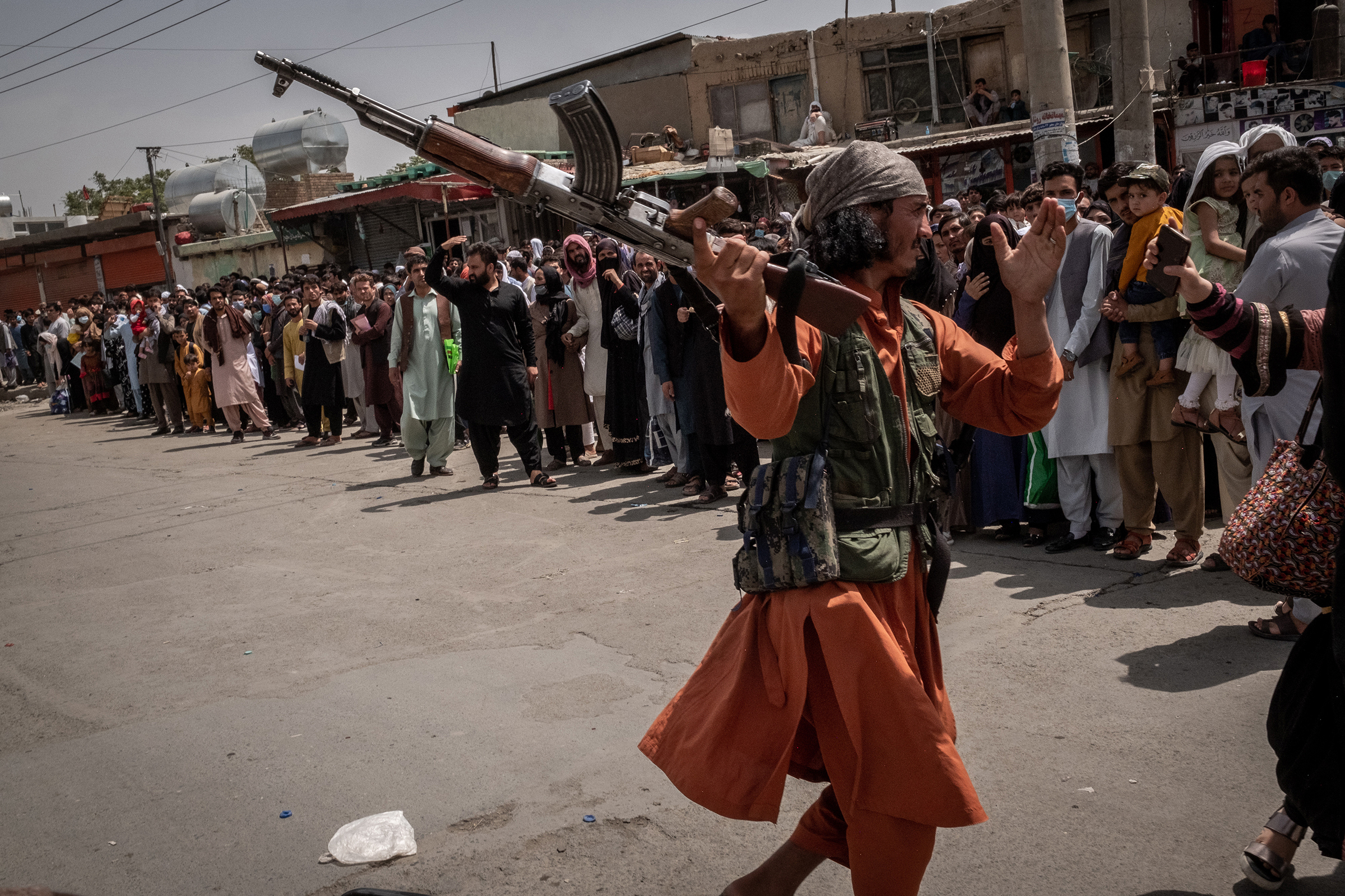 A Taliban member tries to hit a woman, who was waiting to get access to the international airport with her family and others in order to flee the country, in Kabul on Aug. 18, 2021.