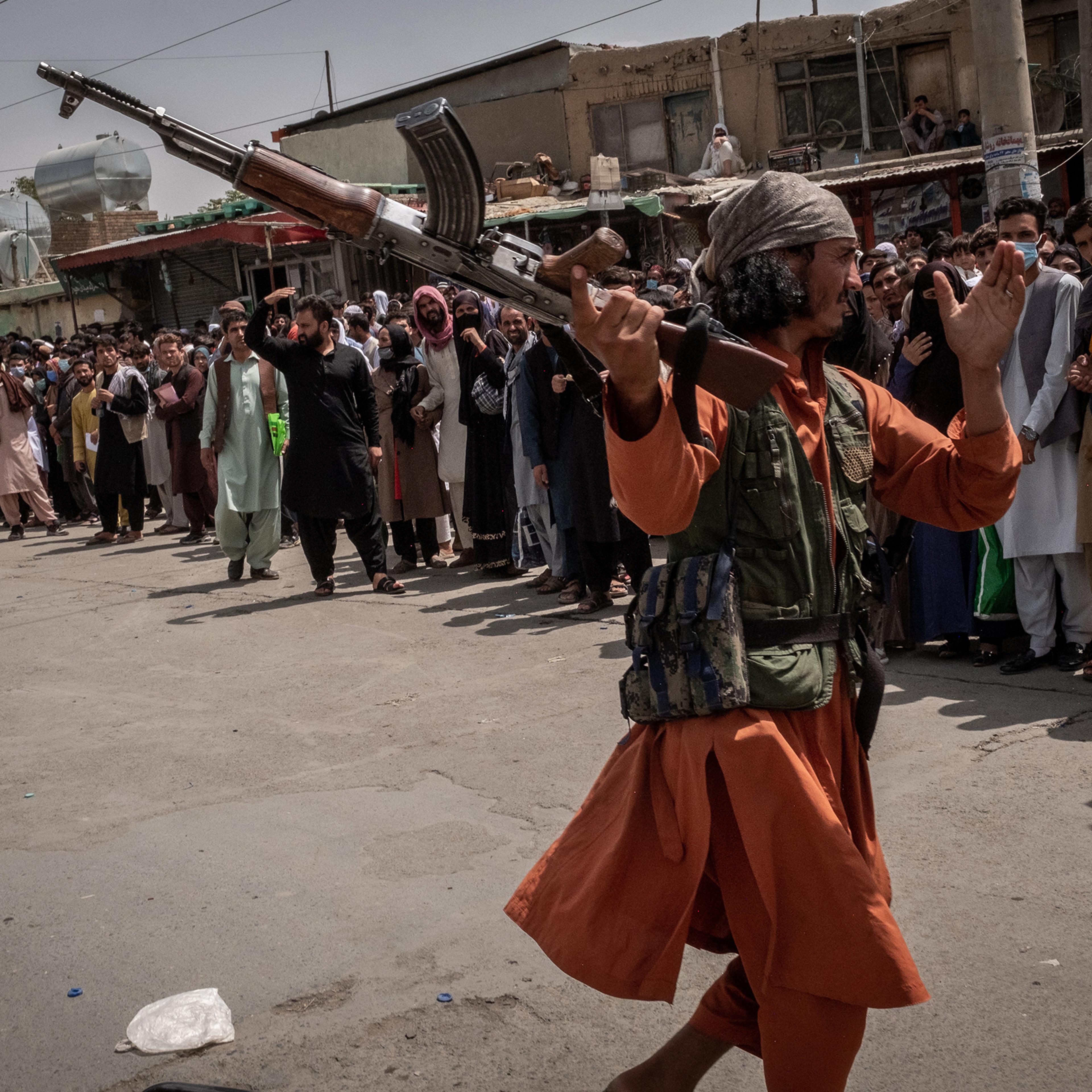 A Taliban member tries to hit a woman, who was waiting to get access to the international airport with her family and others in order to flee the country, in Kabul on Aug. 18, 2021.