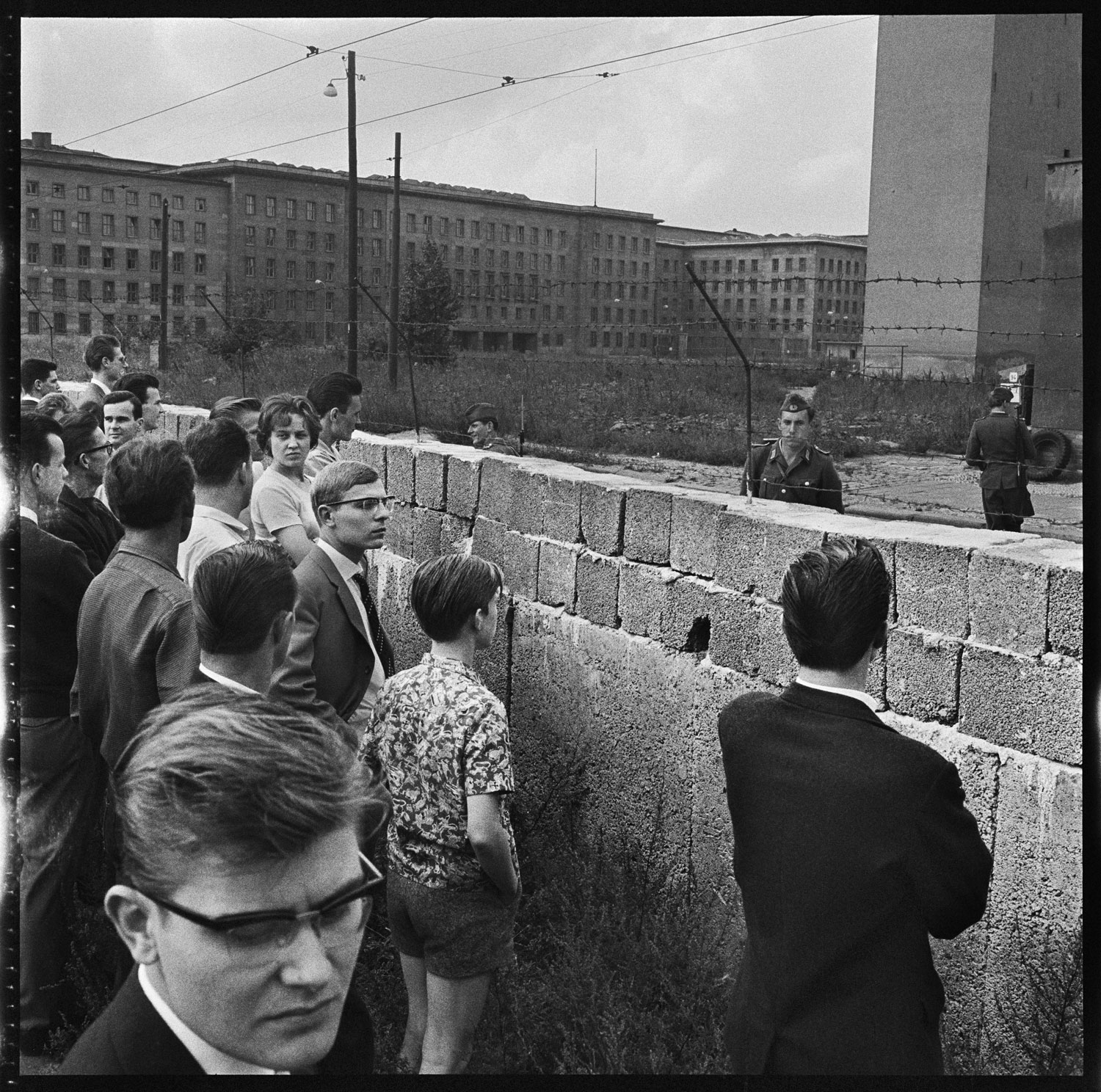 West Berliners looking over a portion of the Berlin Wall at the time of its construction. East German soldiers looking back, West Berlin, Germany, August 1961.