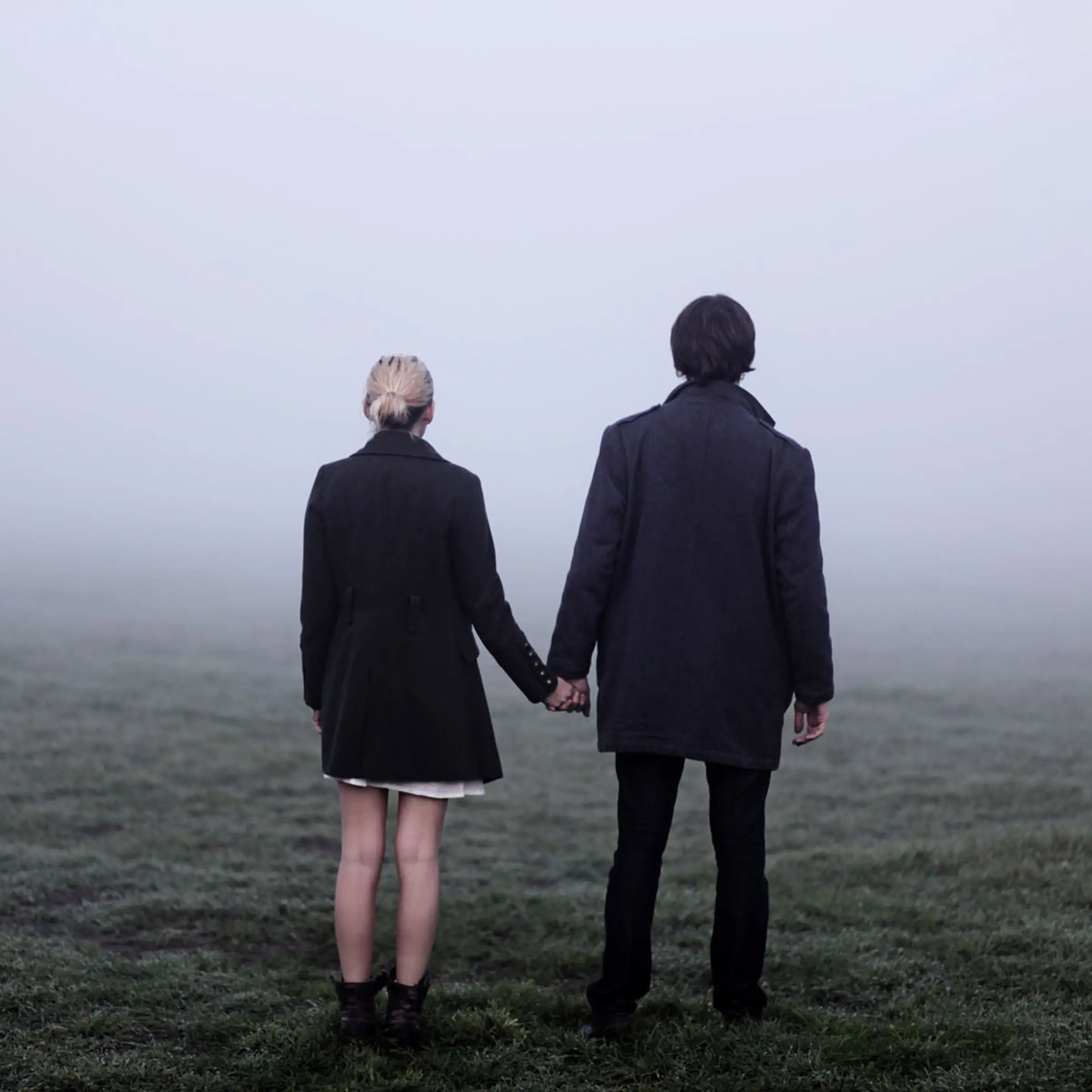 Couple holding hands outside in thick fog.