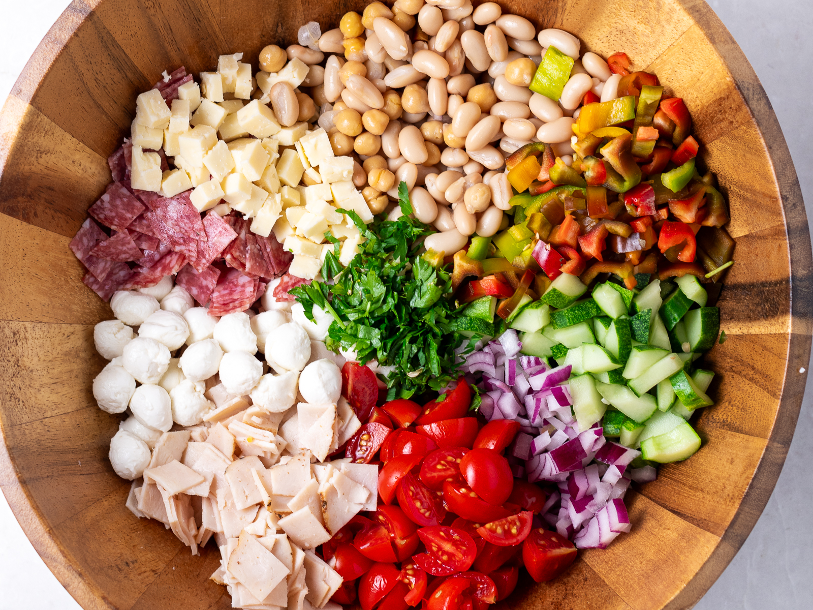 Registered dietitian Erica Baty prepares a dense bean salad with ingredients including garbanzo beans, white beans, salami, cherry tomatoes, sharp chedder, and parsley.