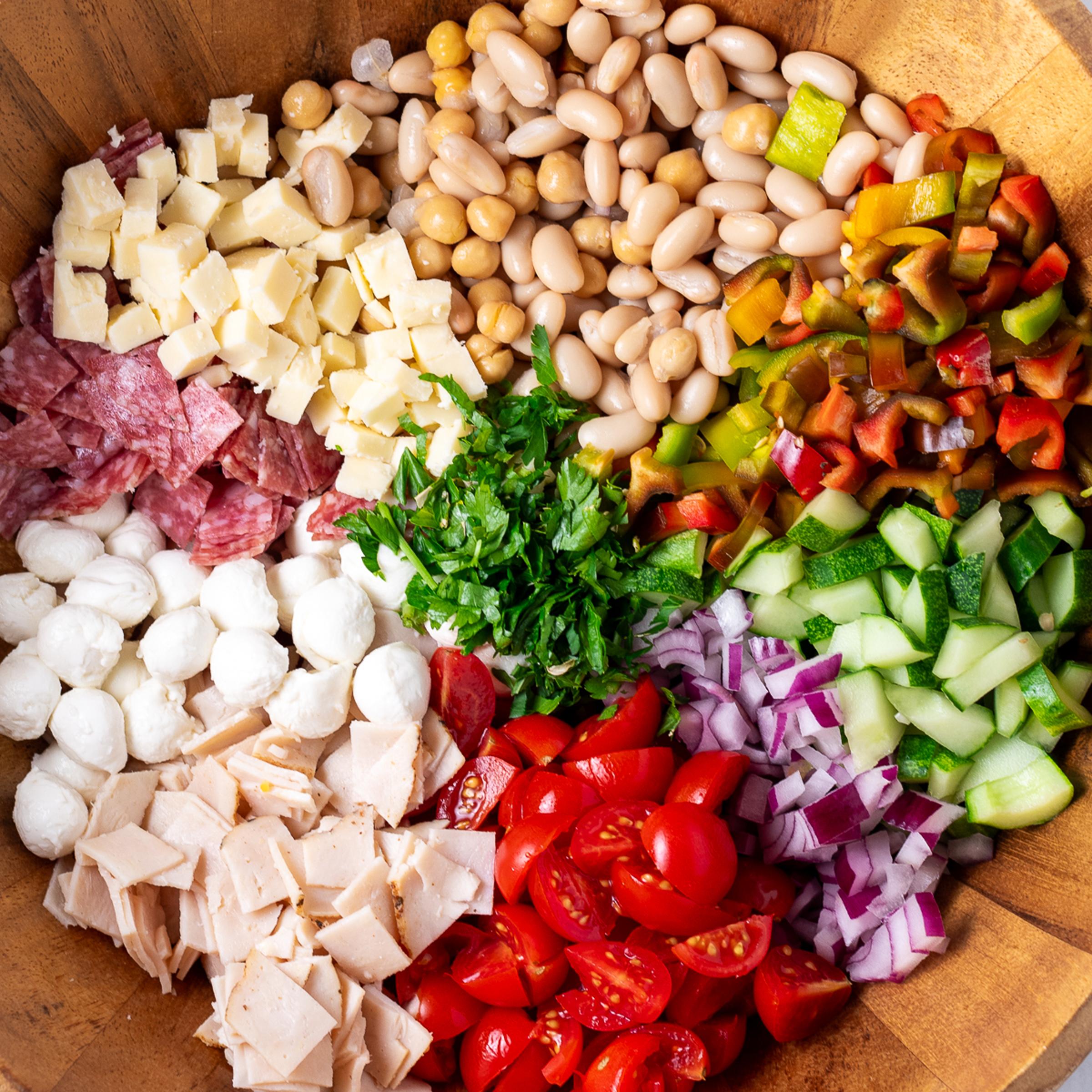 Registered dietitian Erica Baty prepares a dense bean salad with ingredients including garbanzo beans, white beans, salami, cherry tomatoes, sharp chedder, and parsley.
