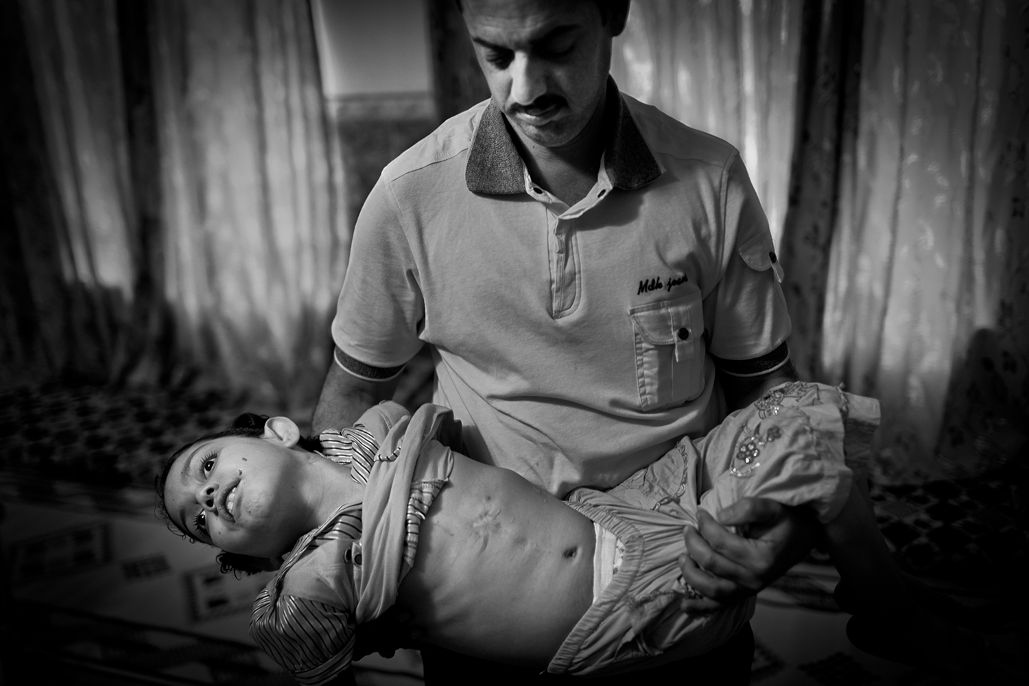 Apr. 18, 2012. Fallujah. A man holds his daughter, who became sick from swallowing dust from the road after the war in 2003.