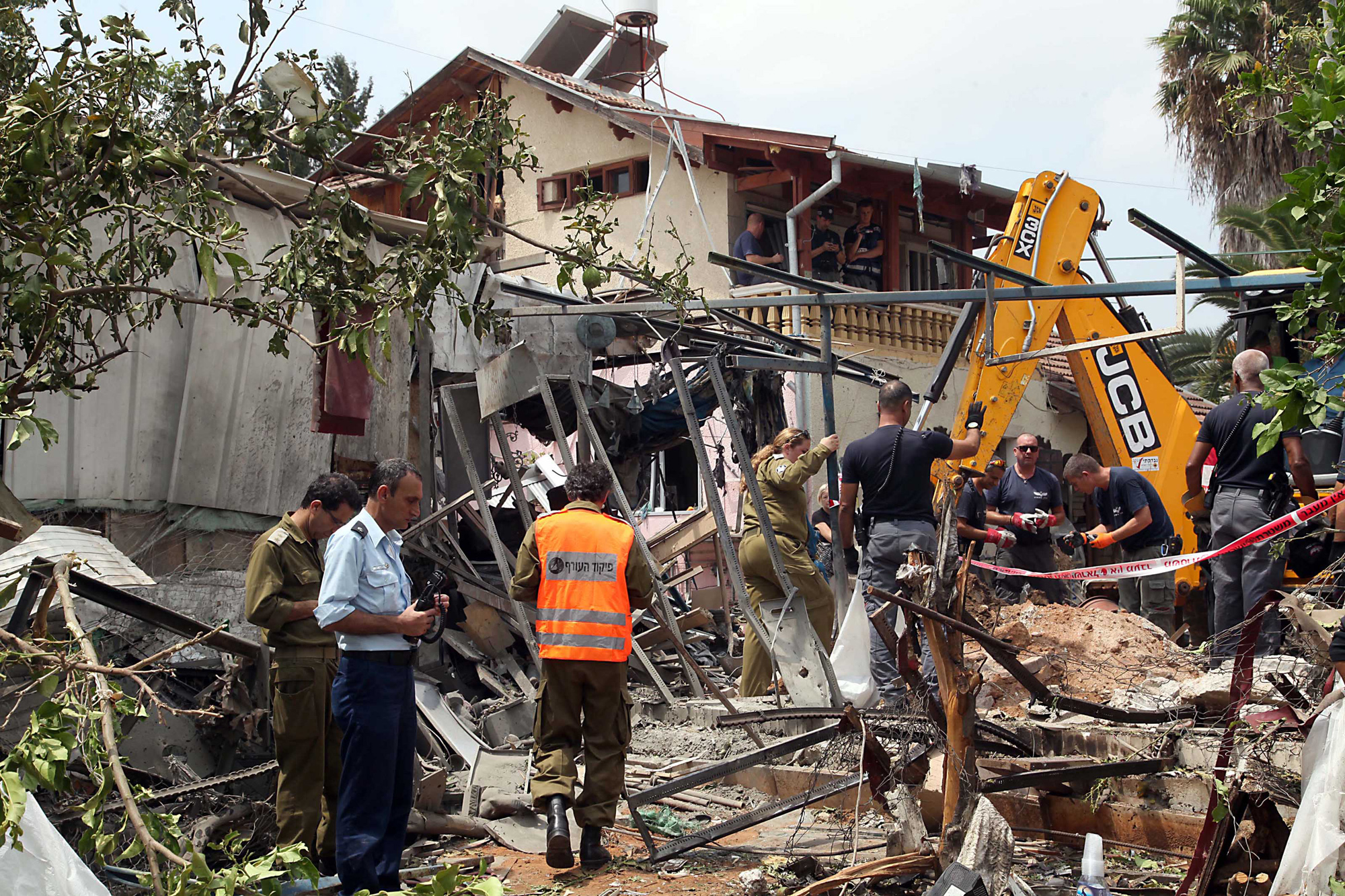 Israeli rescue and military personnel at the wreckage of a home in the town of Yehud, outside Tel Aviv, and near the Ben Gurion Airport, that was hit by a missile fired by Palestinian militants from inside the Gaza Strip, July 22, 2014.