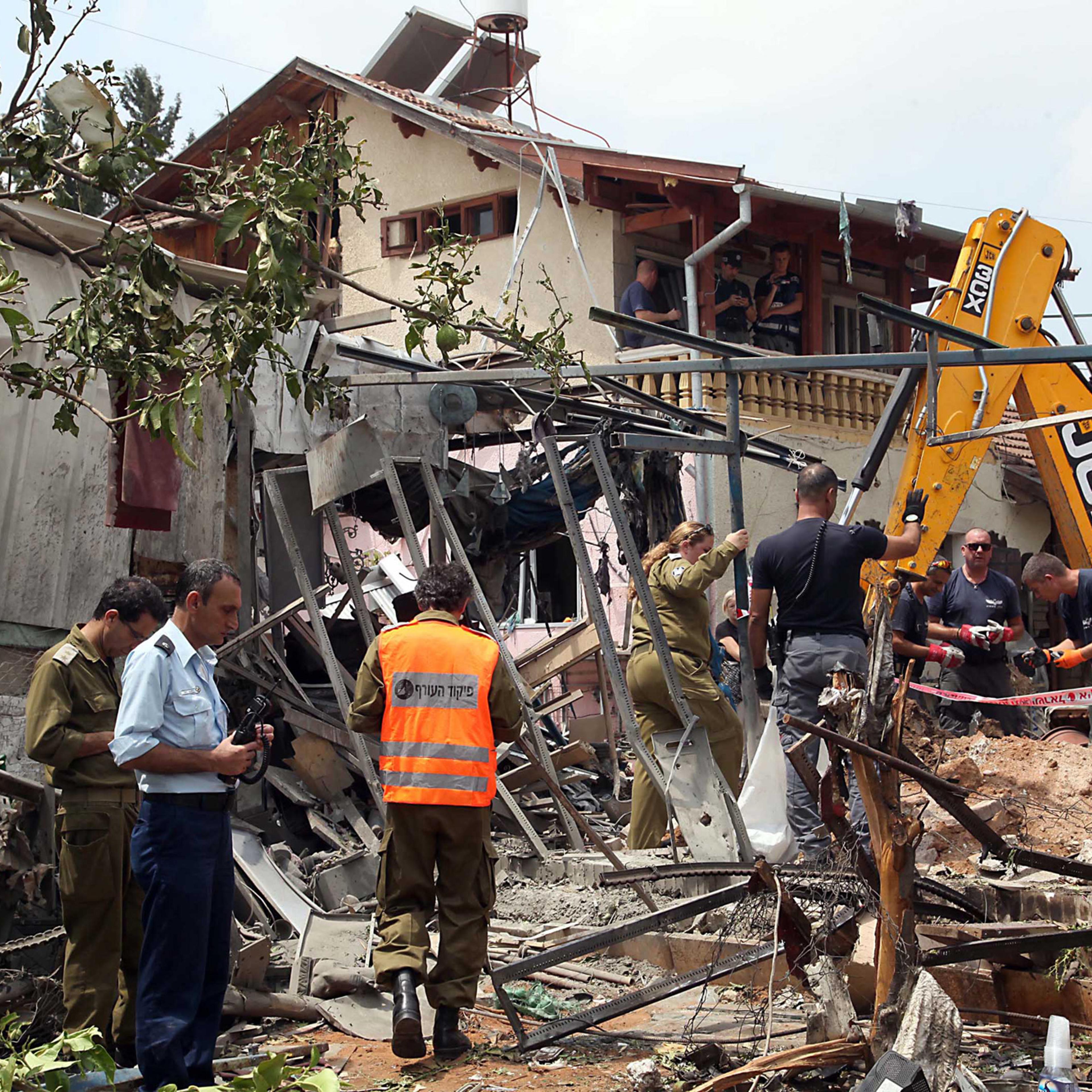 Israeli rescue and military personnel at the wreckage of a home in the town of Yehud, outside Tel Aviv, and near the Ben Gurion Airport, that was hit by a missile fired by Palestinian militants from inside the Gaza Strip, July 22, 2014.