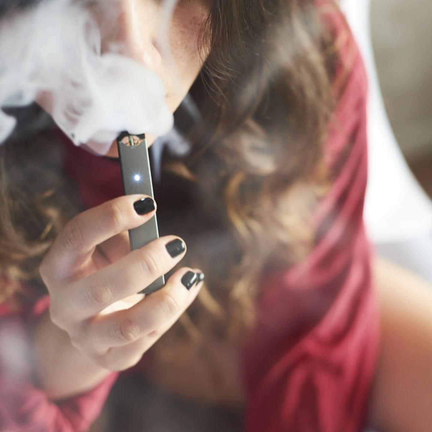 A woman uses a Juul e-cigarette