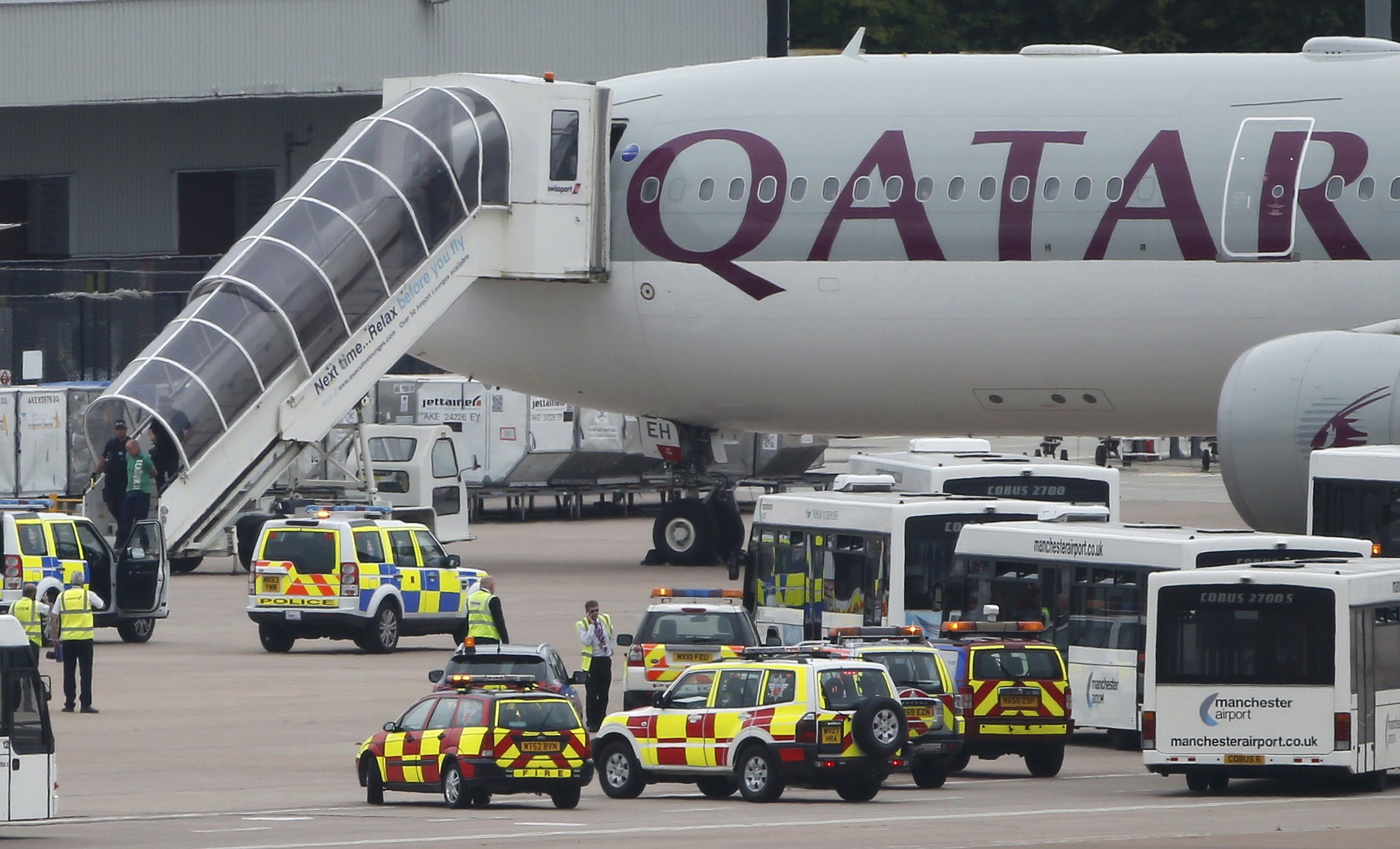 A man is escorted off a Qatar Airways aircraft by police at Manchester airport in Manchester, England on August 5, 2014. A British fighter jet escorted a passenger plane into Manchester airport on Tuesday after the pilot reported that a suspect device wa