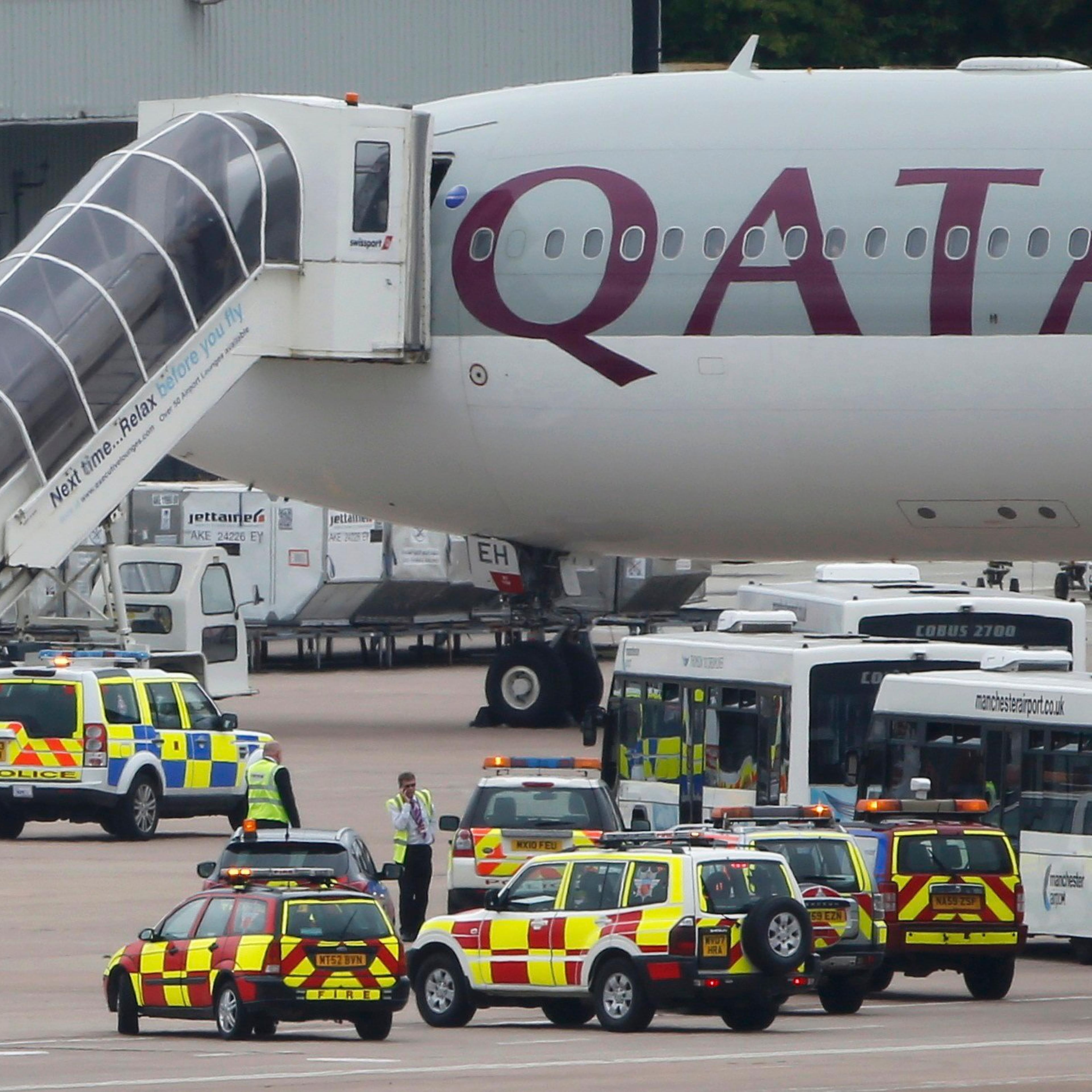 A man is escorted off a Qatar Airways aircraft by police at Manchester airport in Manchester, England on August 5, 2014. A British fighter jet escorted a passenger plane into Manchester airport on Tuesday after the pilot reported that a suspect device wa