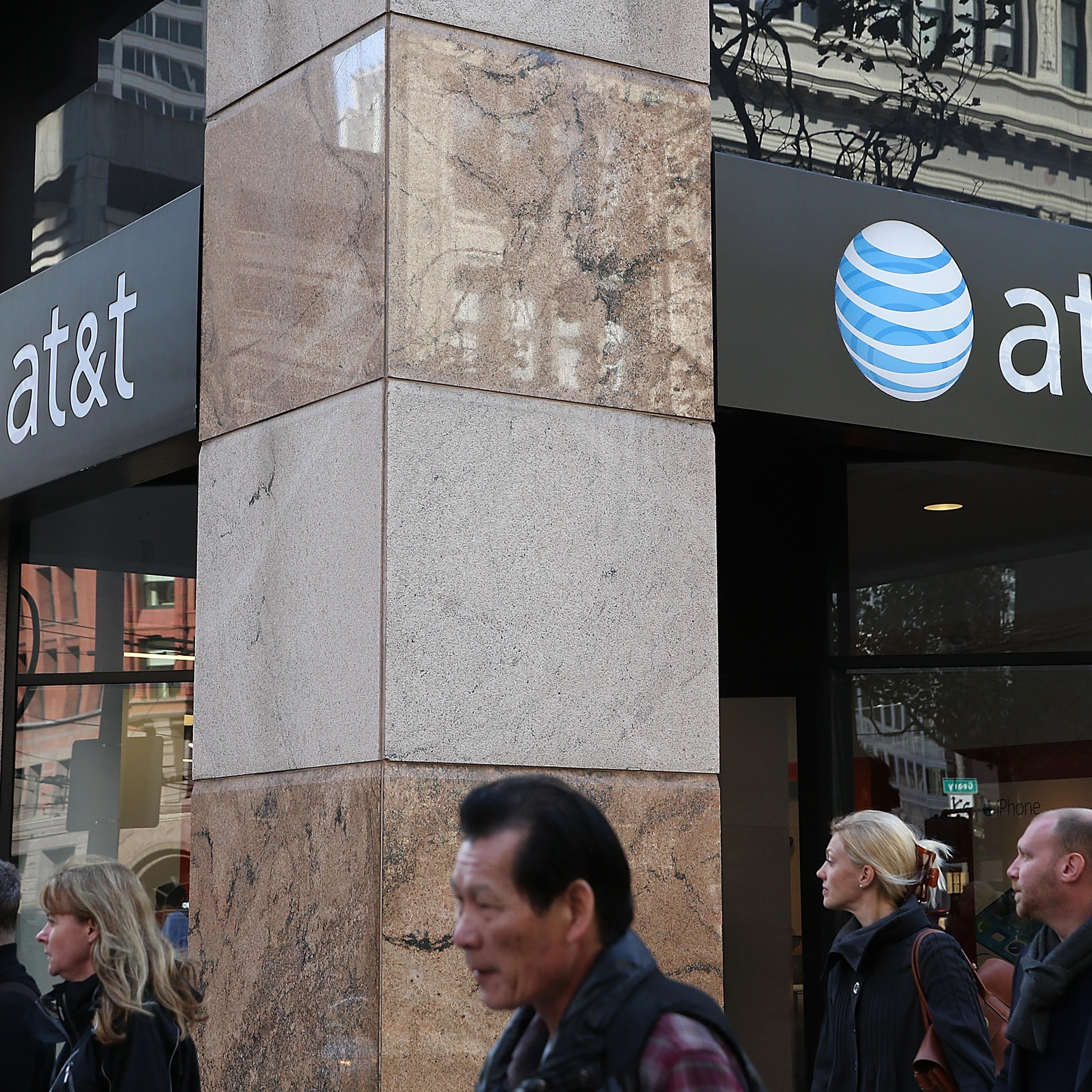 Pedestrians walk by an AT&T store on Oct. 23, 2013 in San Francisco.