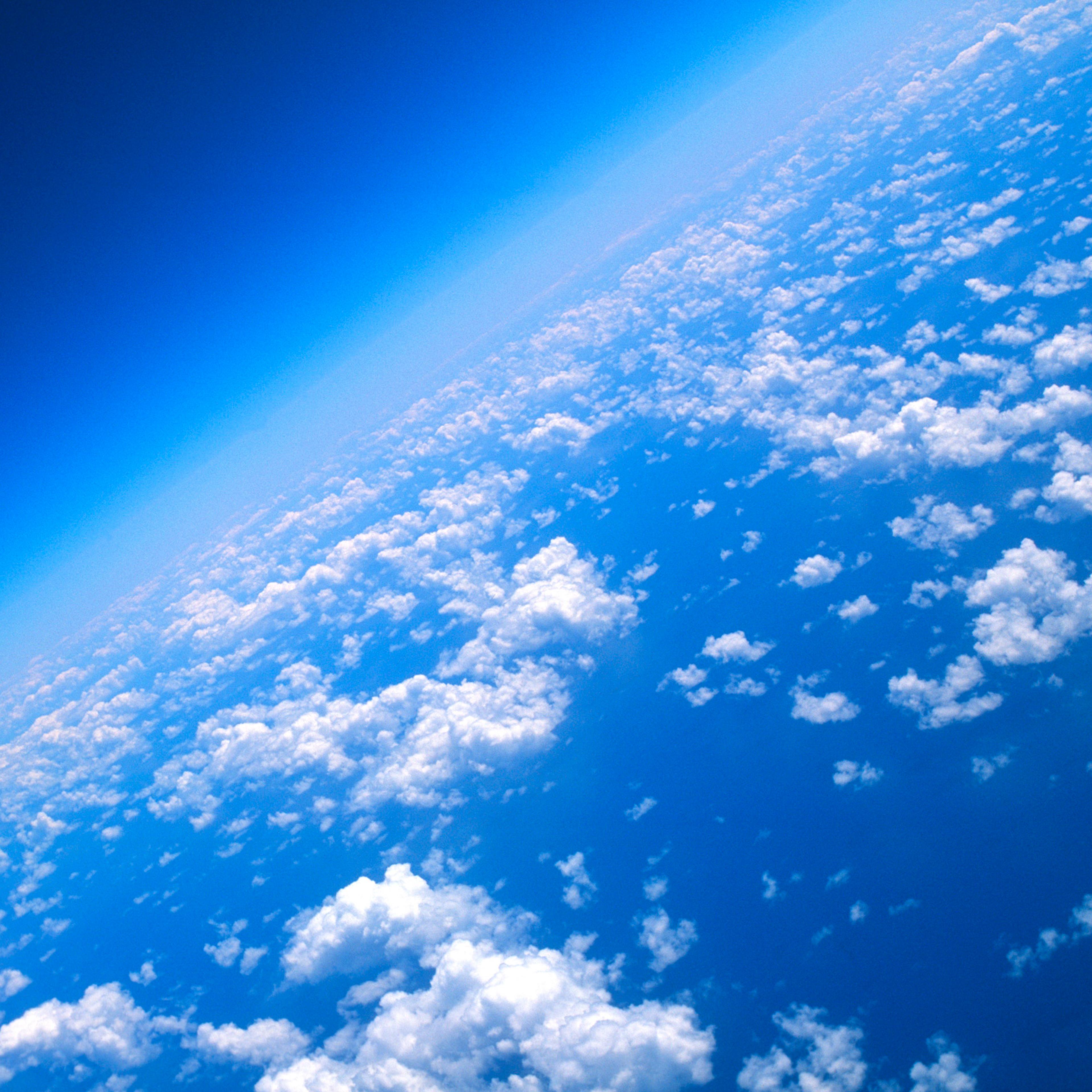 View of world from 40000 feet, clouds and blue sea.